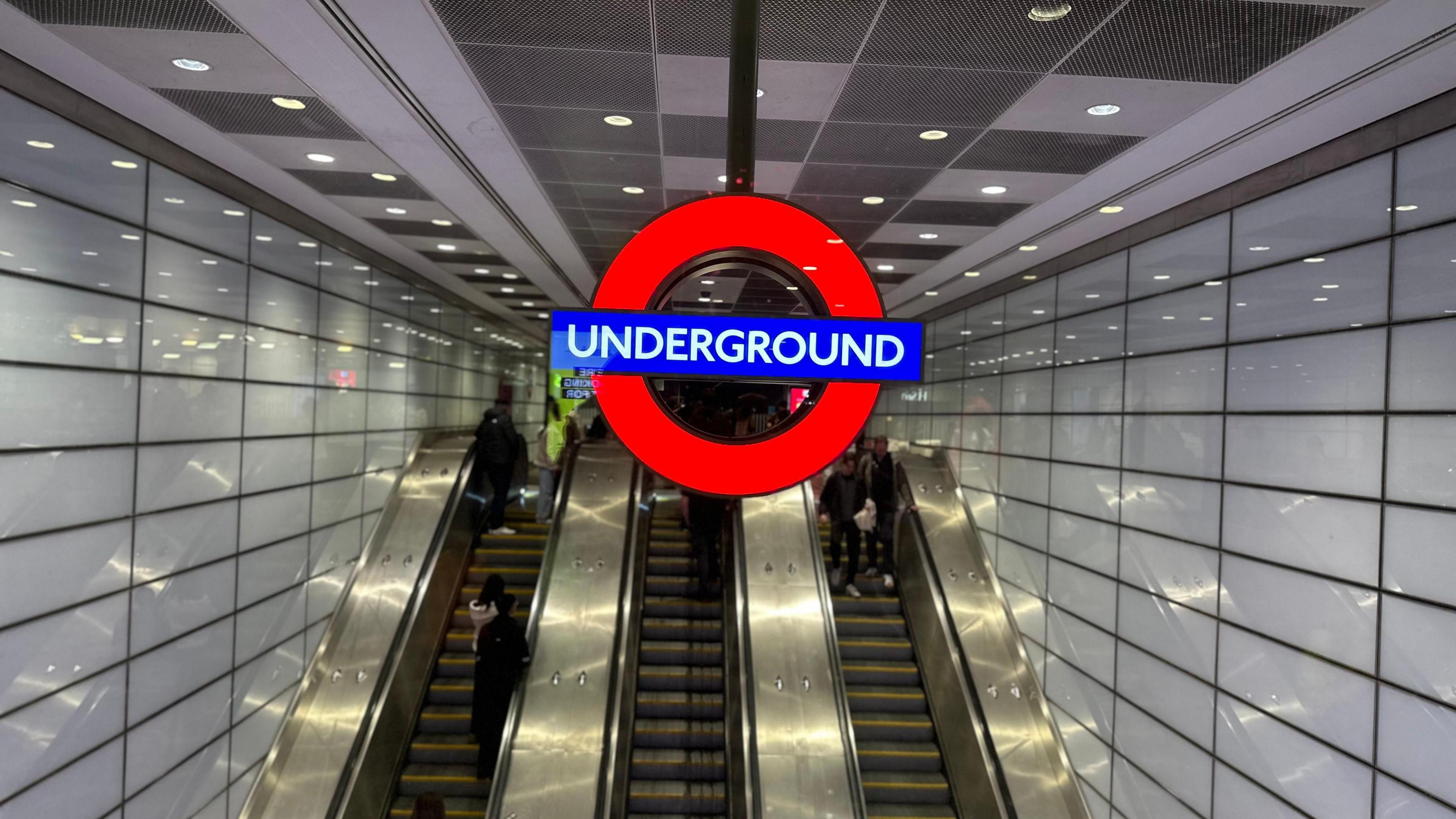 The Tube roundel is hanging above escalators that go down to Euston station