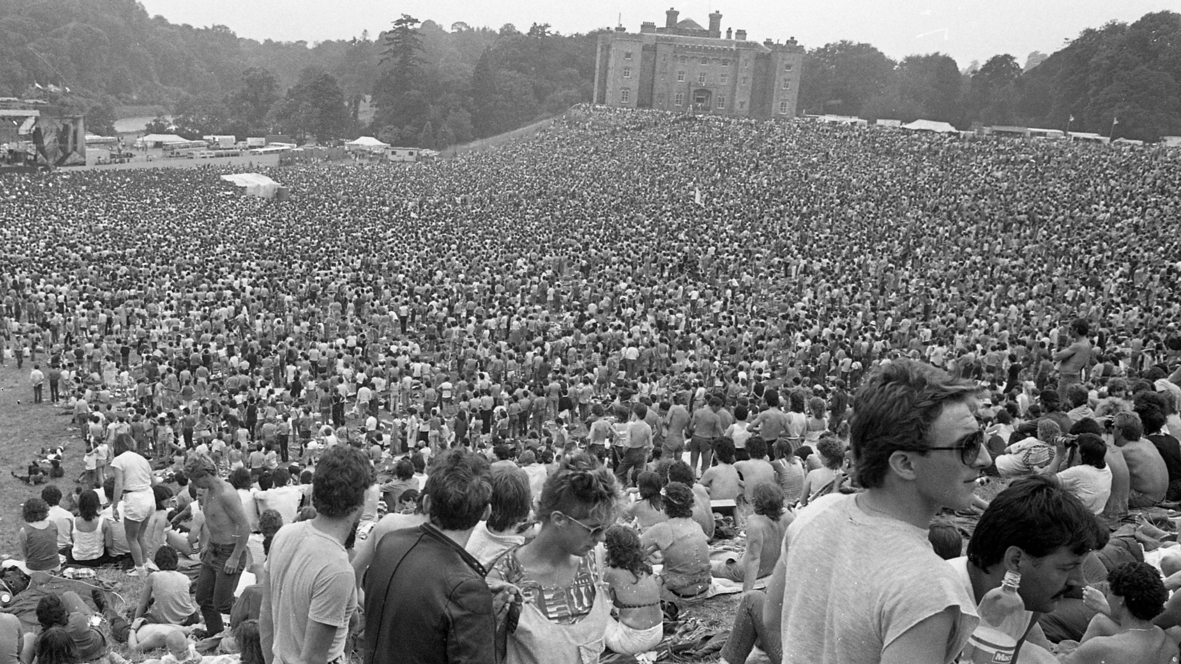 A black and white photo of crowds on the grass by Slane Castle.