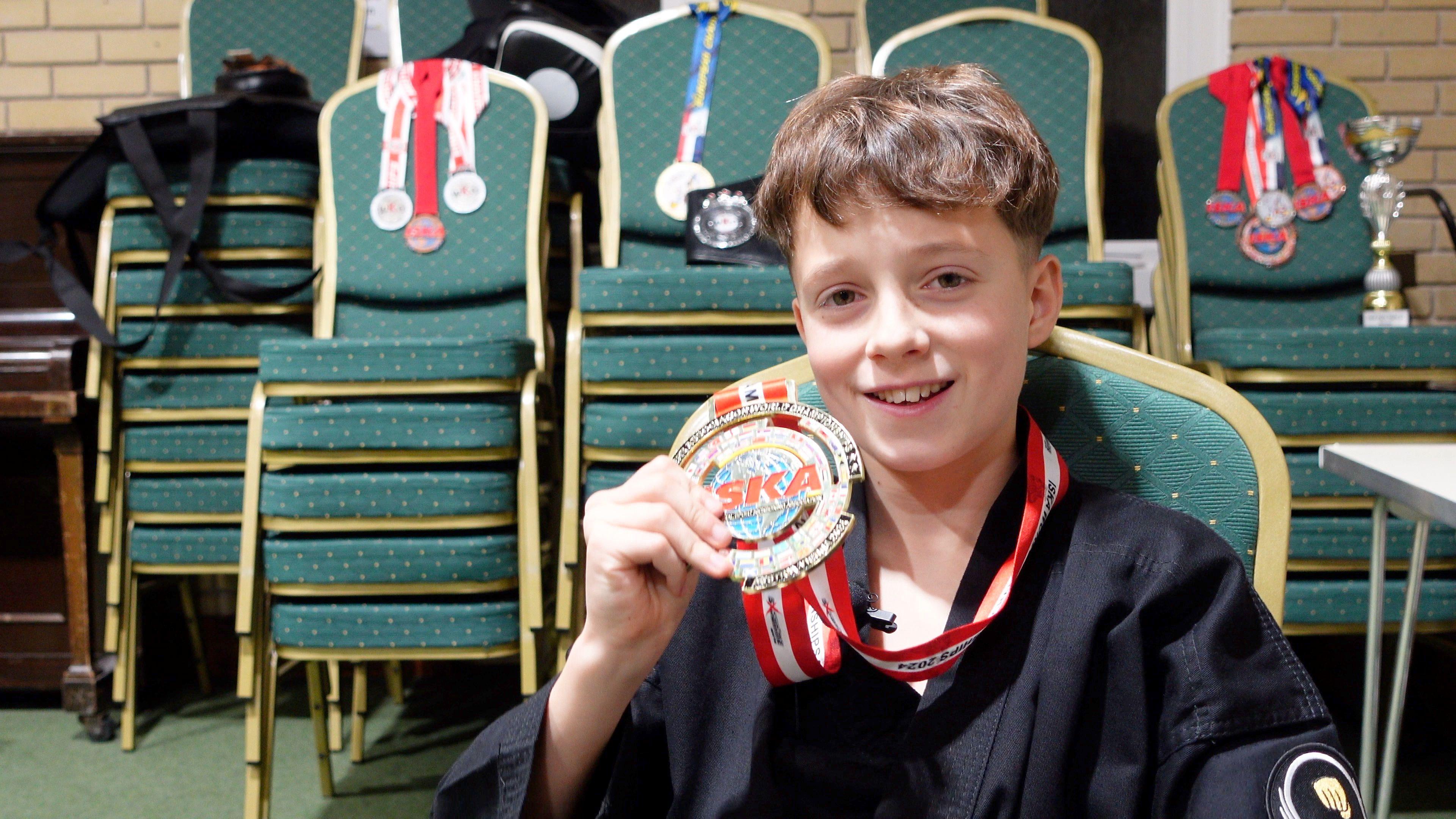 Seb smiles directly into the camera holding his gold medal