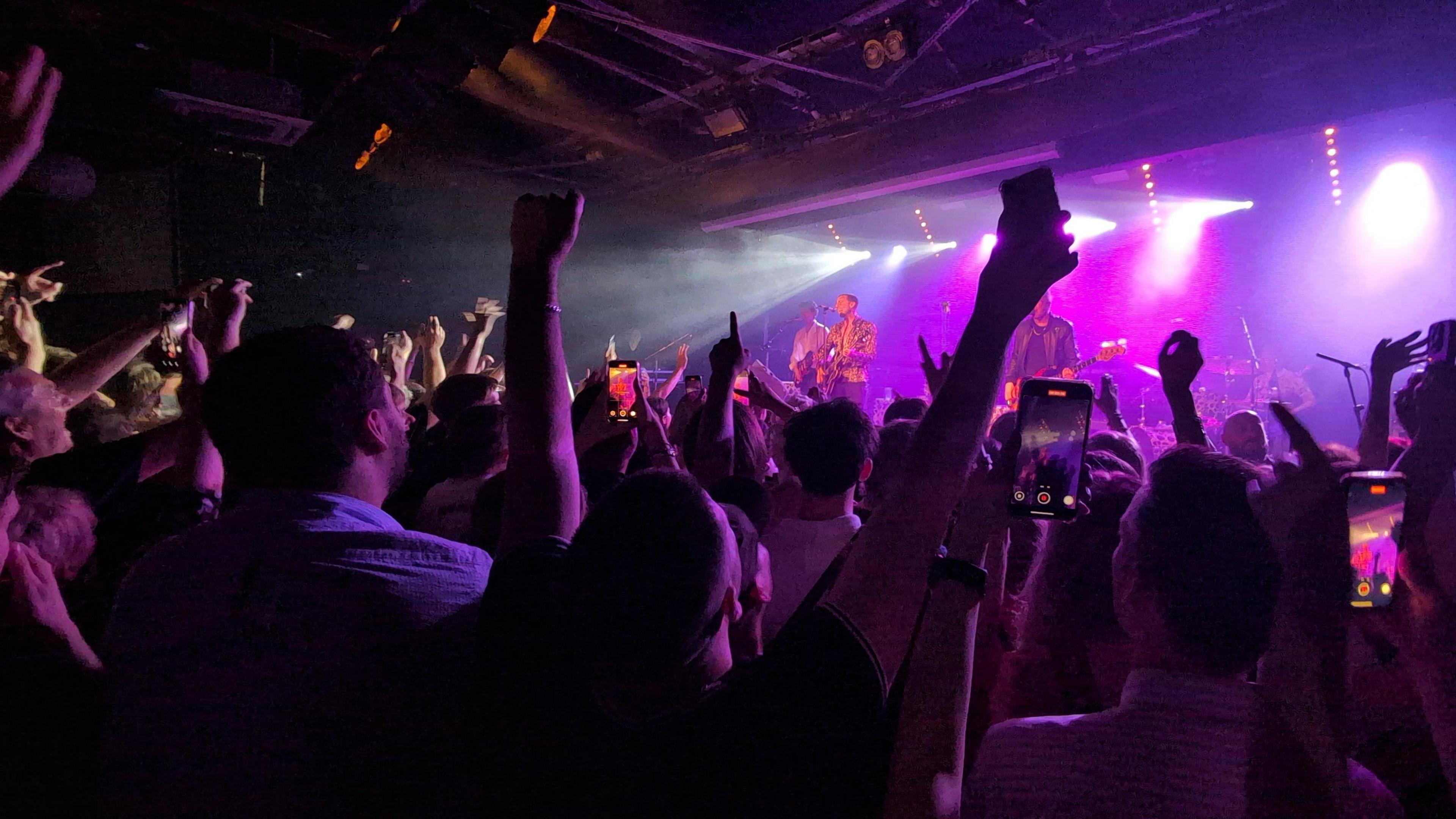 A photo of a stage, taken by someone in the crown of gig attendees. A black poster at the back says "the leadmill" on it. It appears a small and initimate venue with quite a low stage.