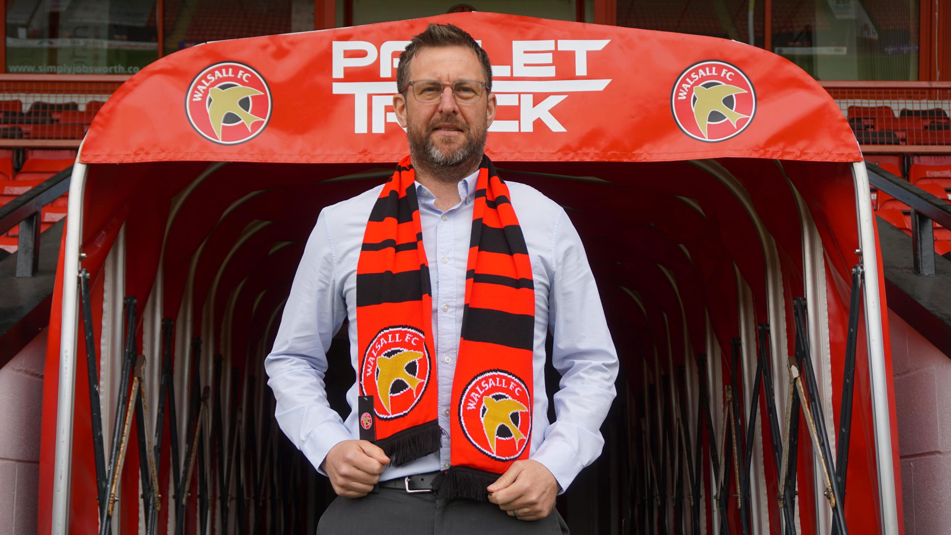 Walsall's new head of football Steward Mairs poses with a club scarf around his neck in front of the tunnel at the Pallet-Track Stadium