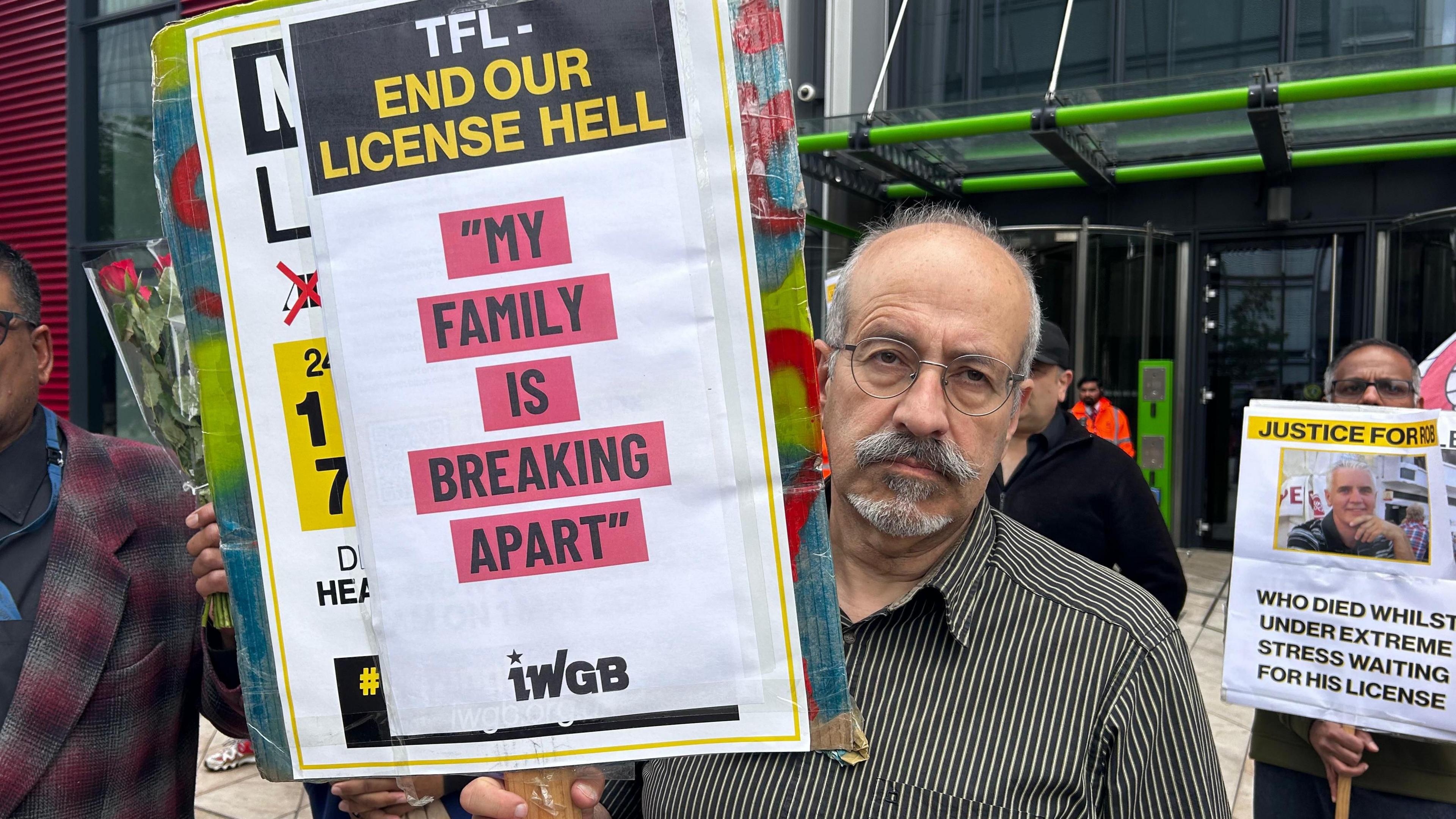 Kambiz Hemati holds up picket of Robert Dale protesting against TfL