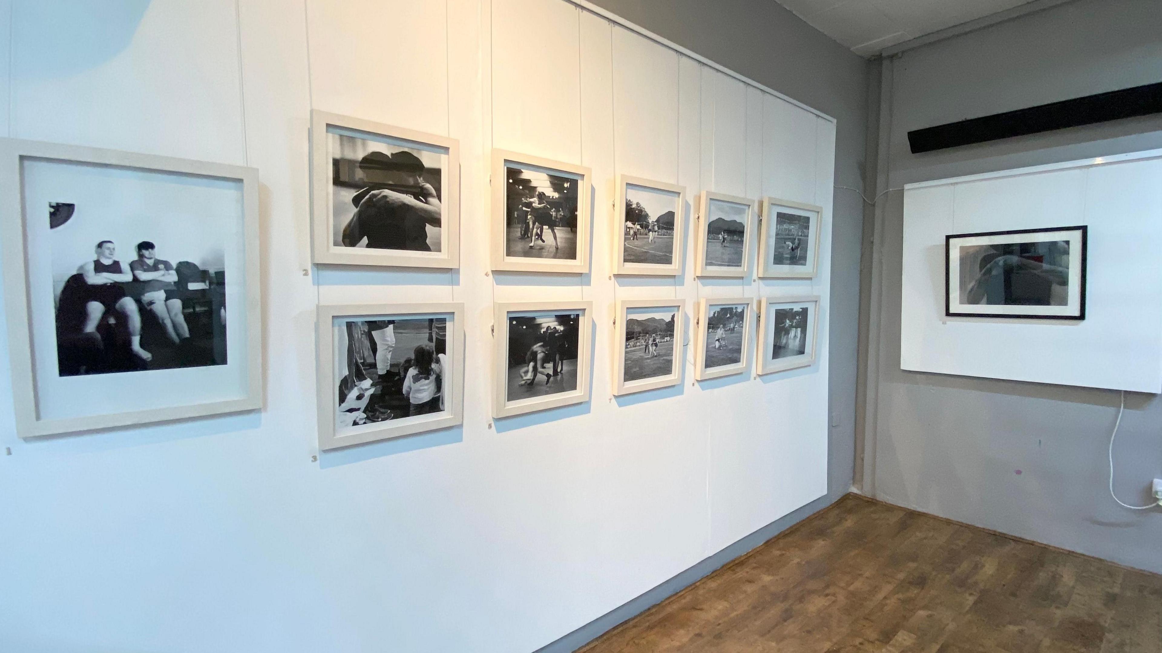 White gallery wall with black-and-white photos of the people involved in Cumberland and Westmorland wrestling.