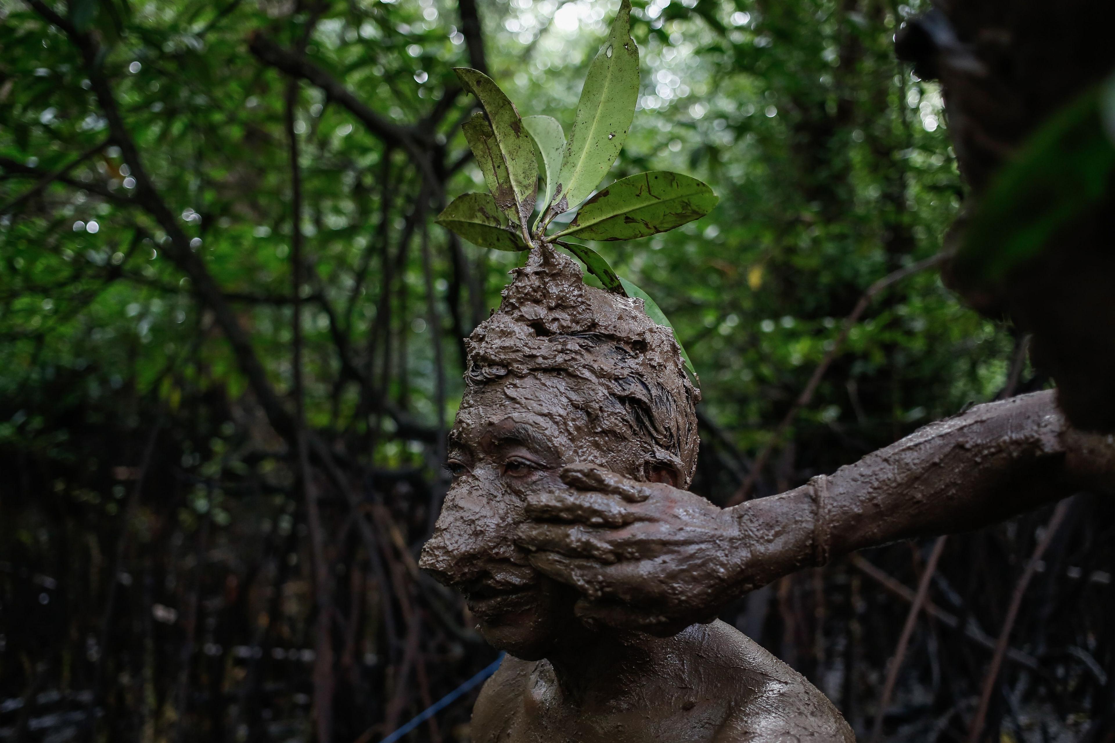 A local Balinese man is covered in mud during a bathing tradition, locally known as Mebuug Buugan, in Kedonganan village, just outside the town of Denpasar, Indonesia