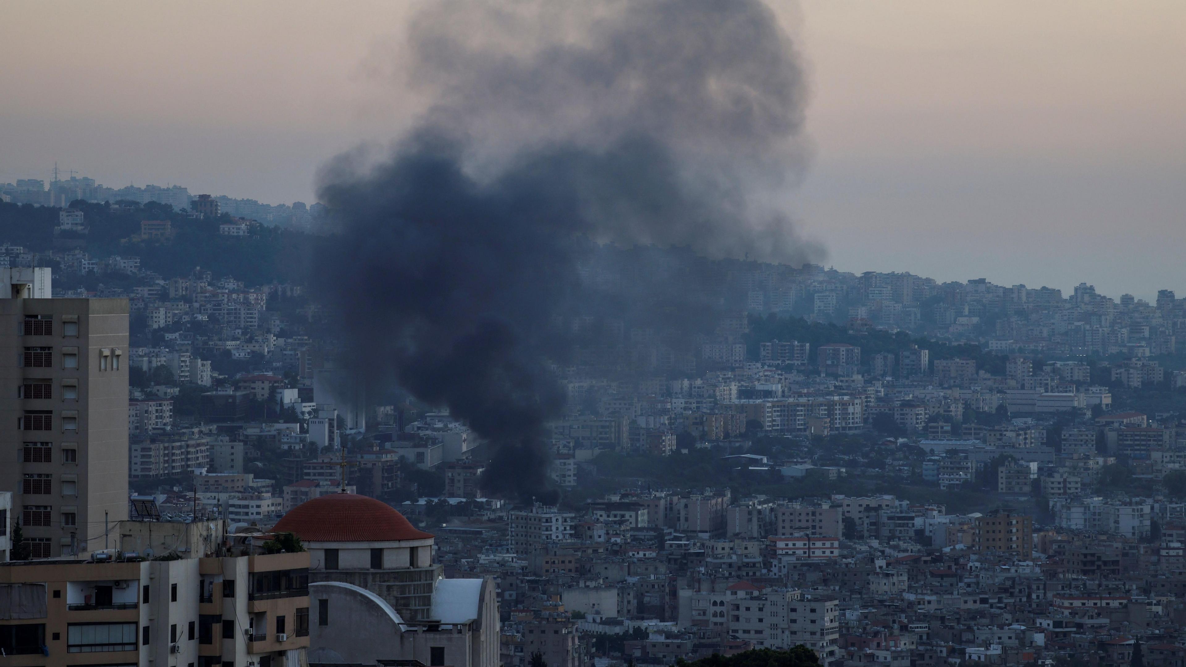 Smoke bellows from a Beirut into the sky. It's a busy city with a lot of buildings.