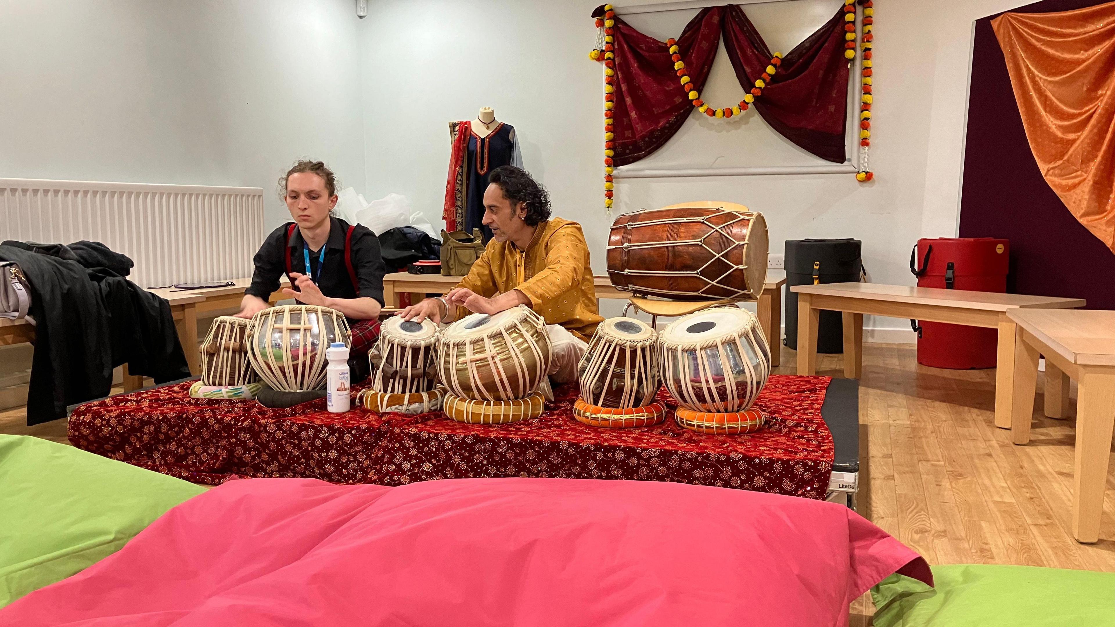 A man and a student playing the tabla and bhaya at the event