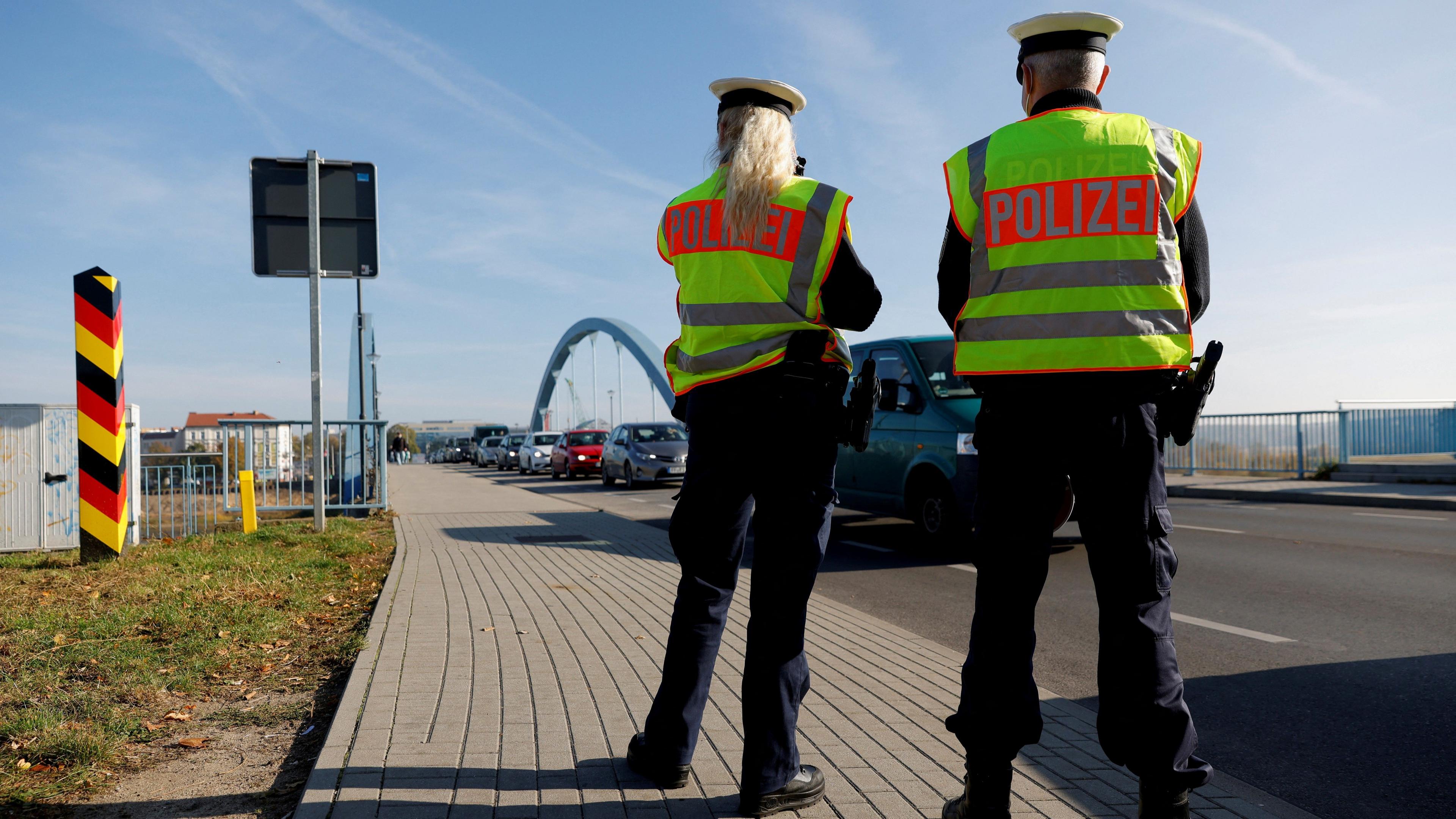 Two German federal police officers patrol a line of cars along the German-Polish border area in order to detain migrants from Belarus in 2021