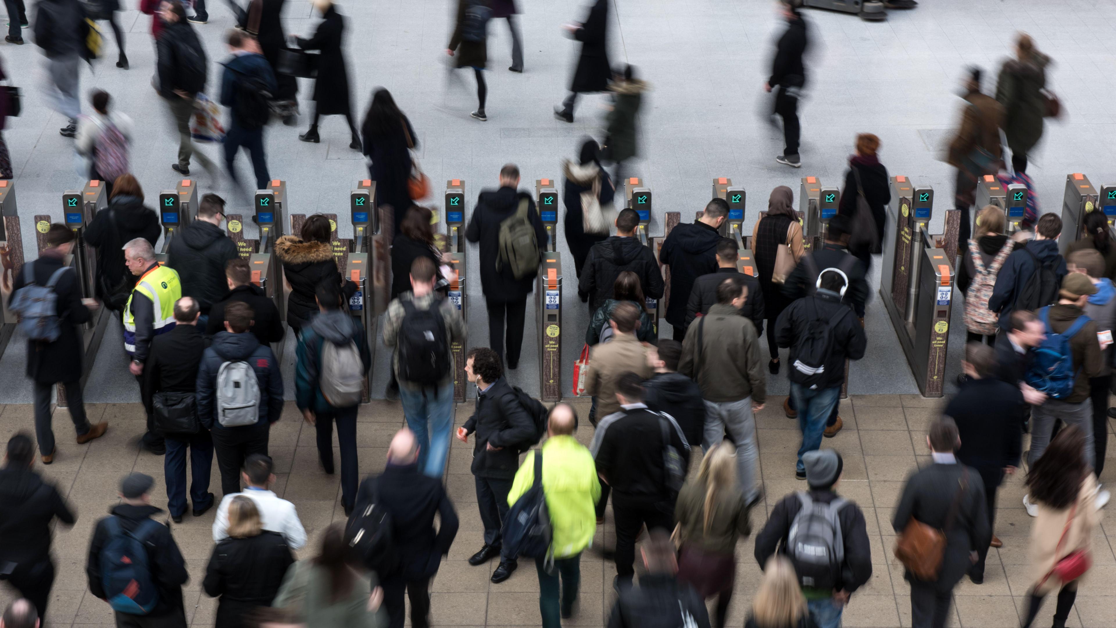 A crowd of people heading towards ticket barriers at Manchester Victoria station. 