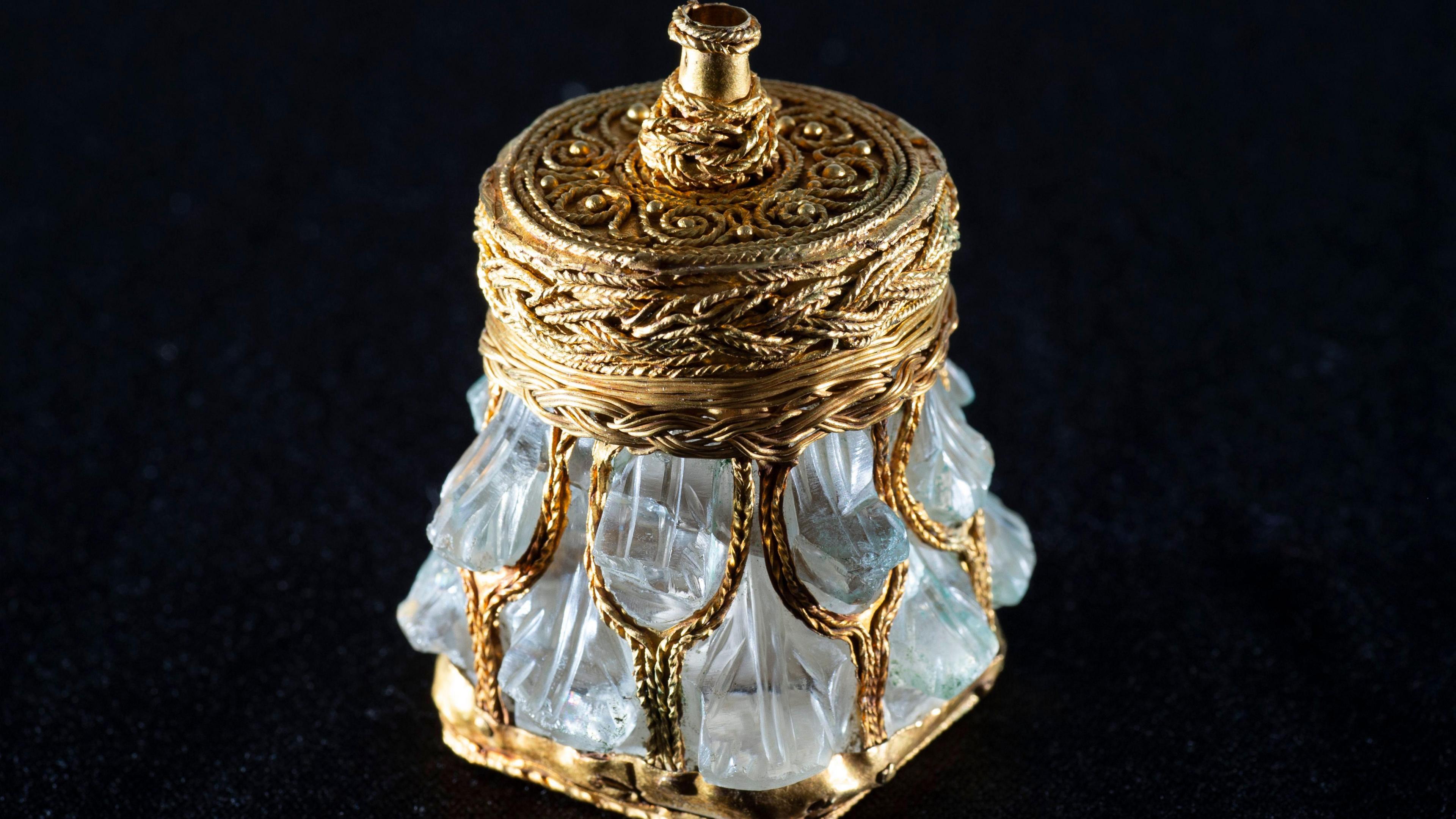 An image of a gold, crystal jar against a black background