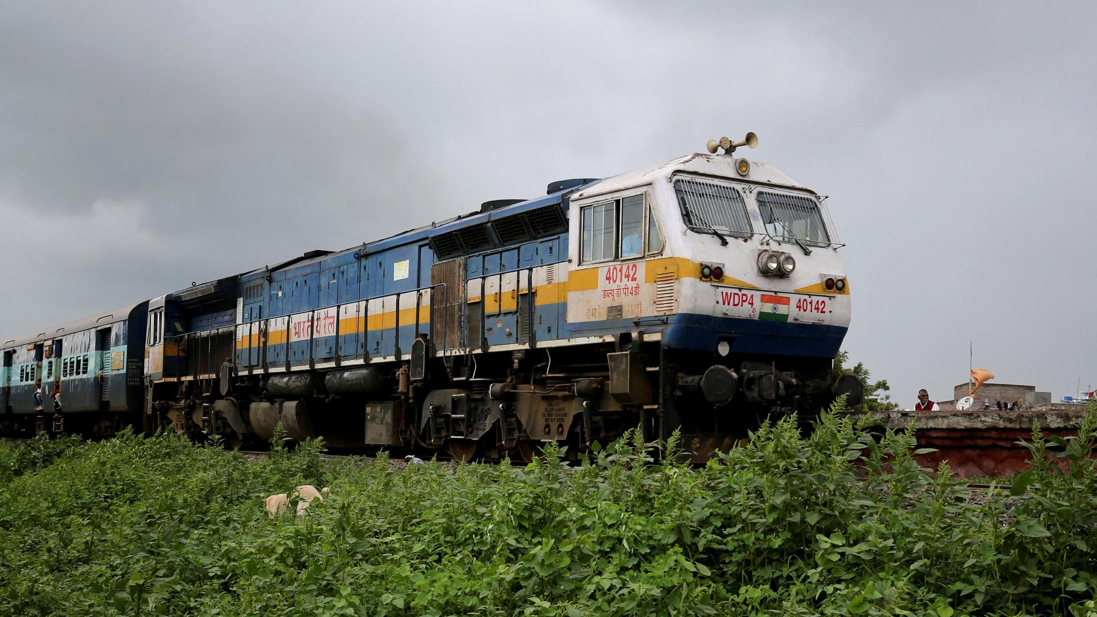 Indian locomotive-hauled train travelling left to right on embankment with green verge in Maharashtra state