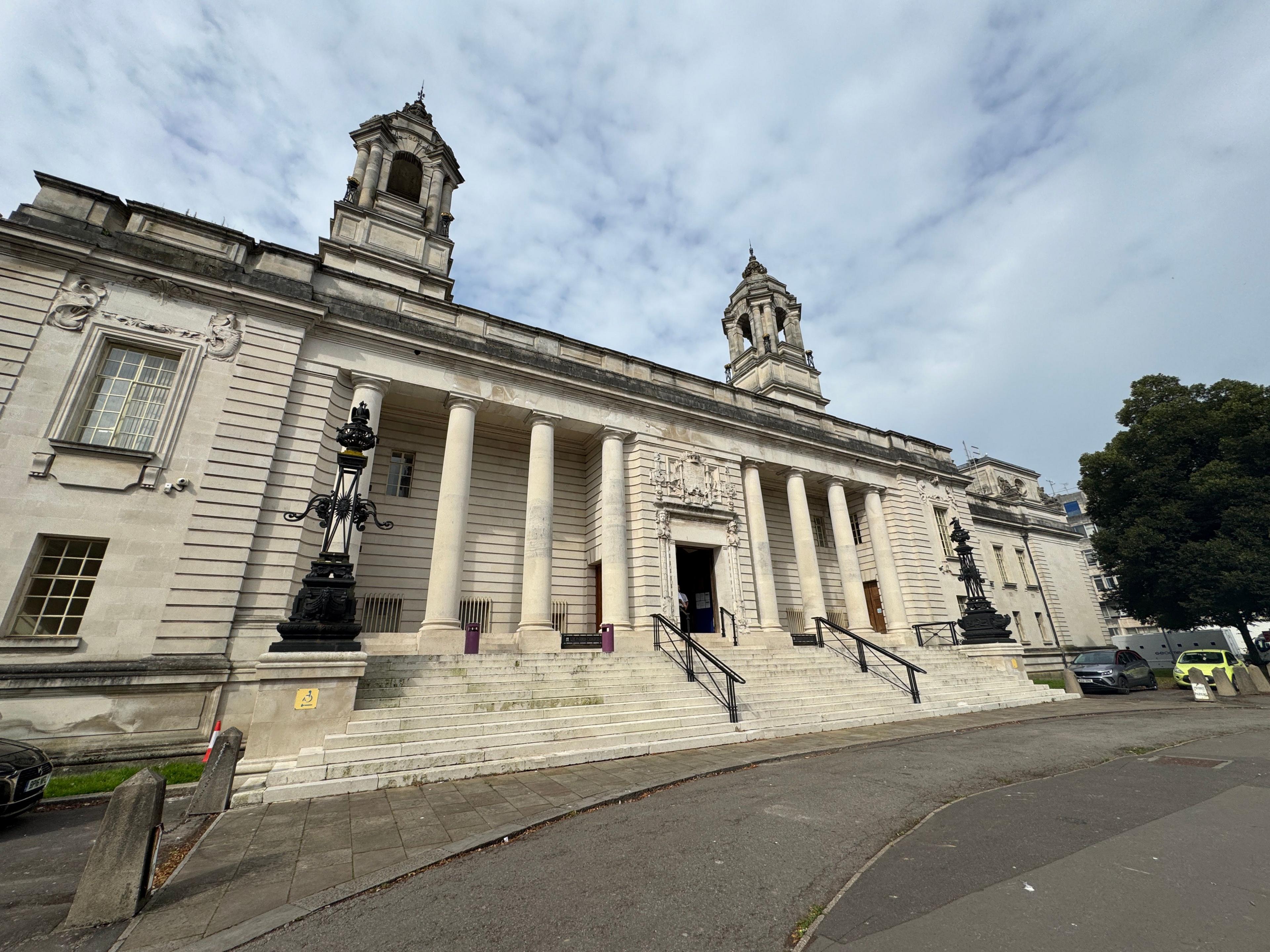 The outside view of Cardiff Crown Court. It is an Edwardian Baroque style building constructed with Portland stone. It has eight small columns and two turrets.