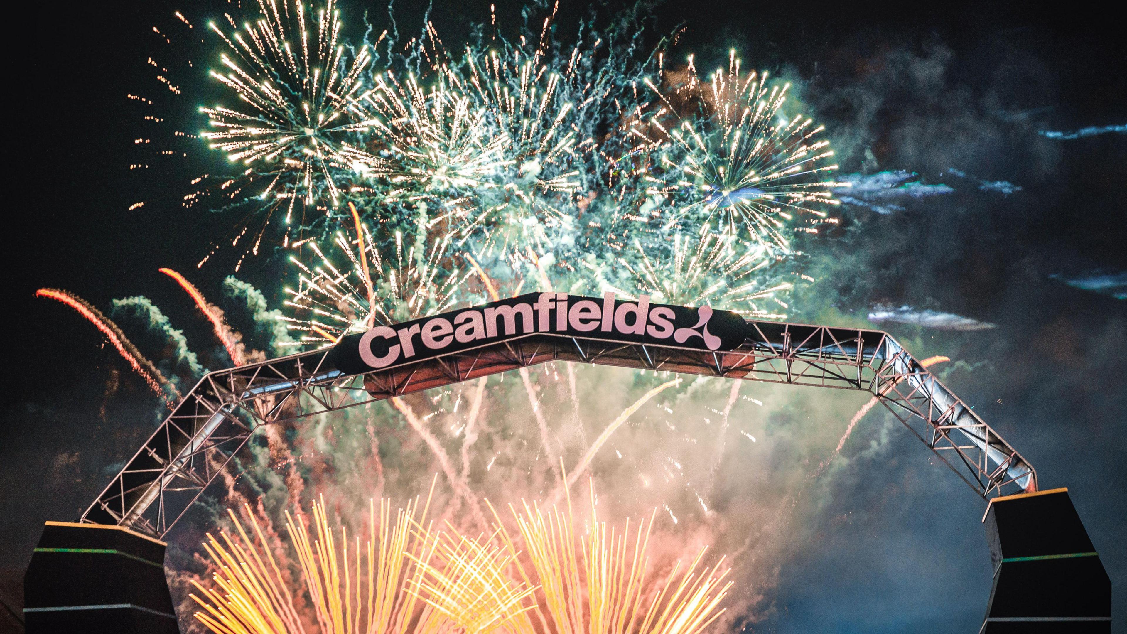 The Creamfields logo at the entrance of the festival site is displayed in front of the night sky lit up with yellow, pink and green fireworks