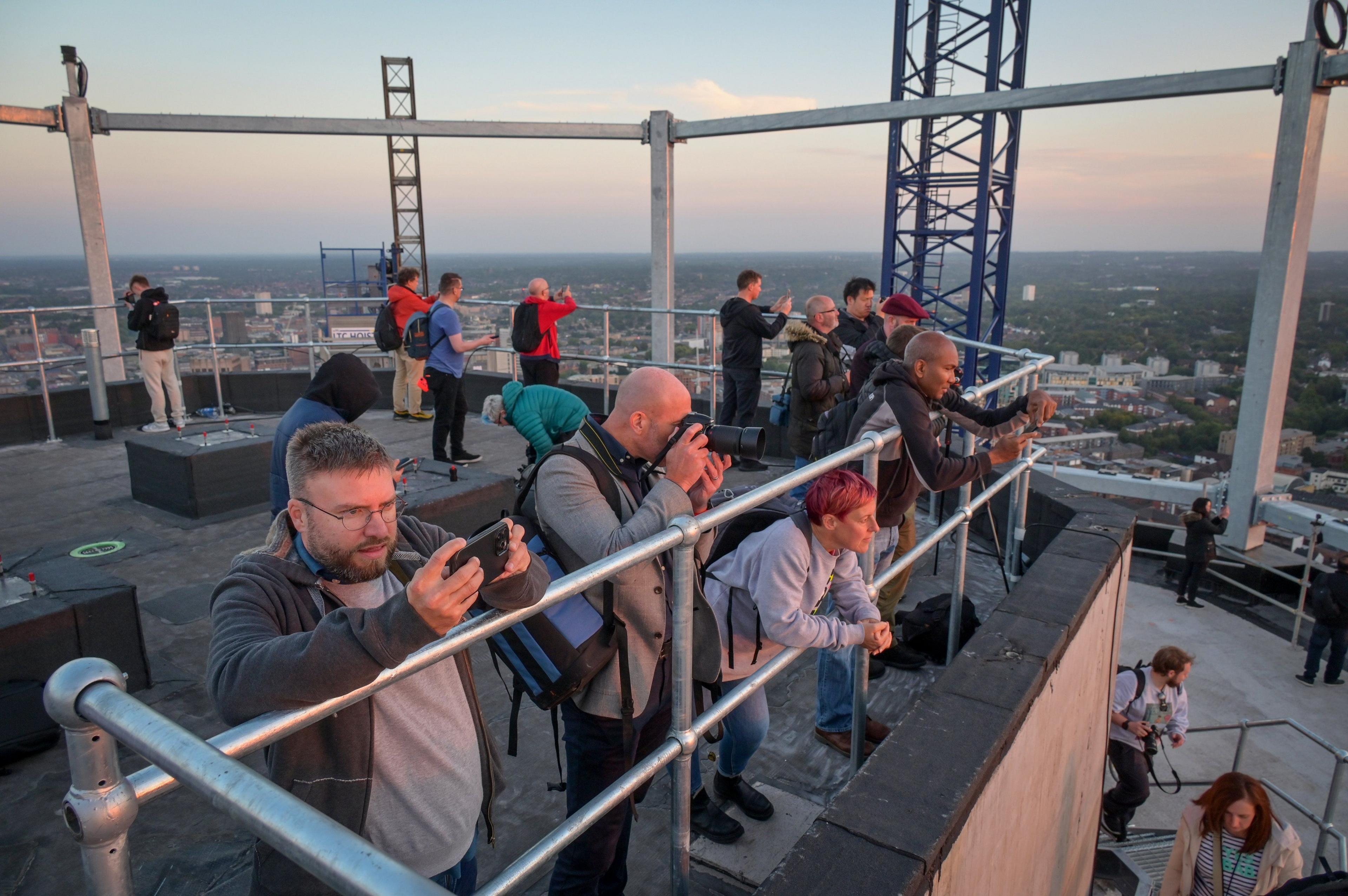 People leaning on barriers taking pictures from the top of the building 