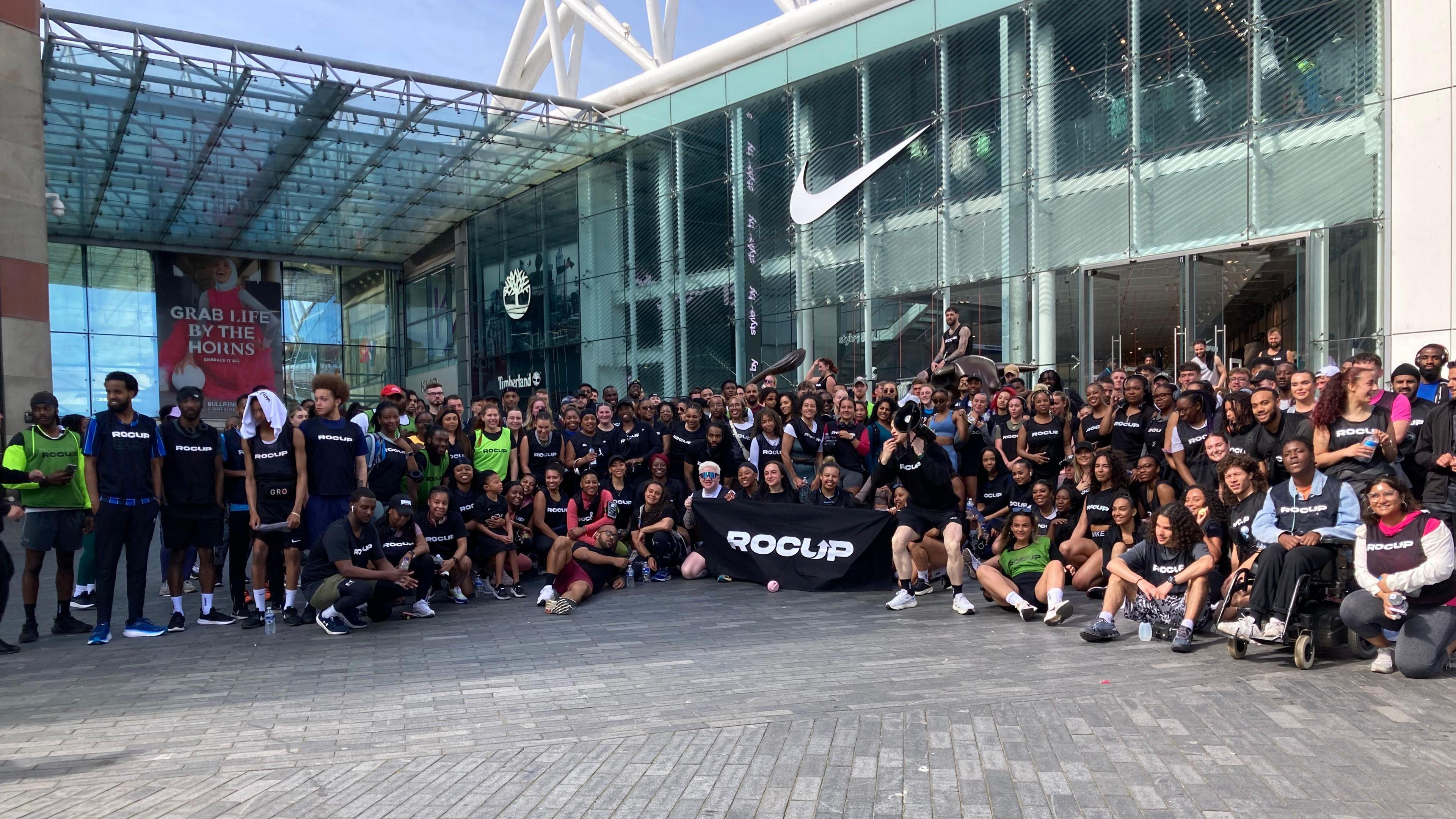 A large group of runners dressed in their running gear stand outside the Bullring shopping centre in Birmingham