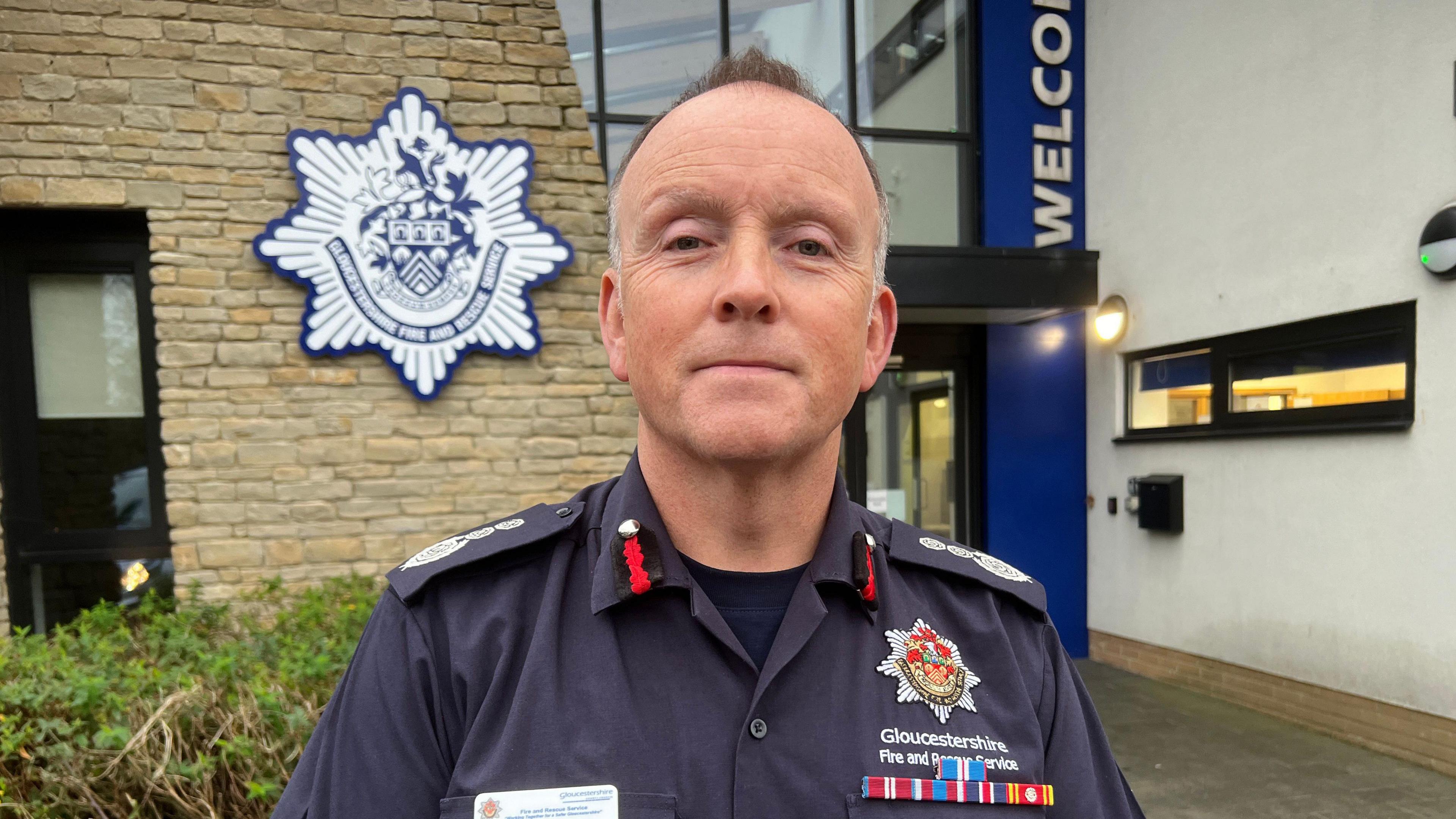 Mark Preece wearing his uniform outside a Gloucestershire Fire and Rescue Service station