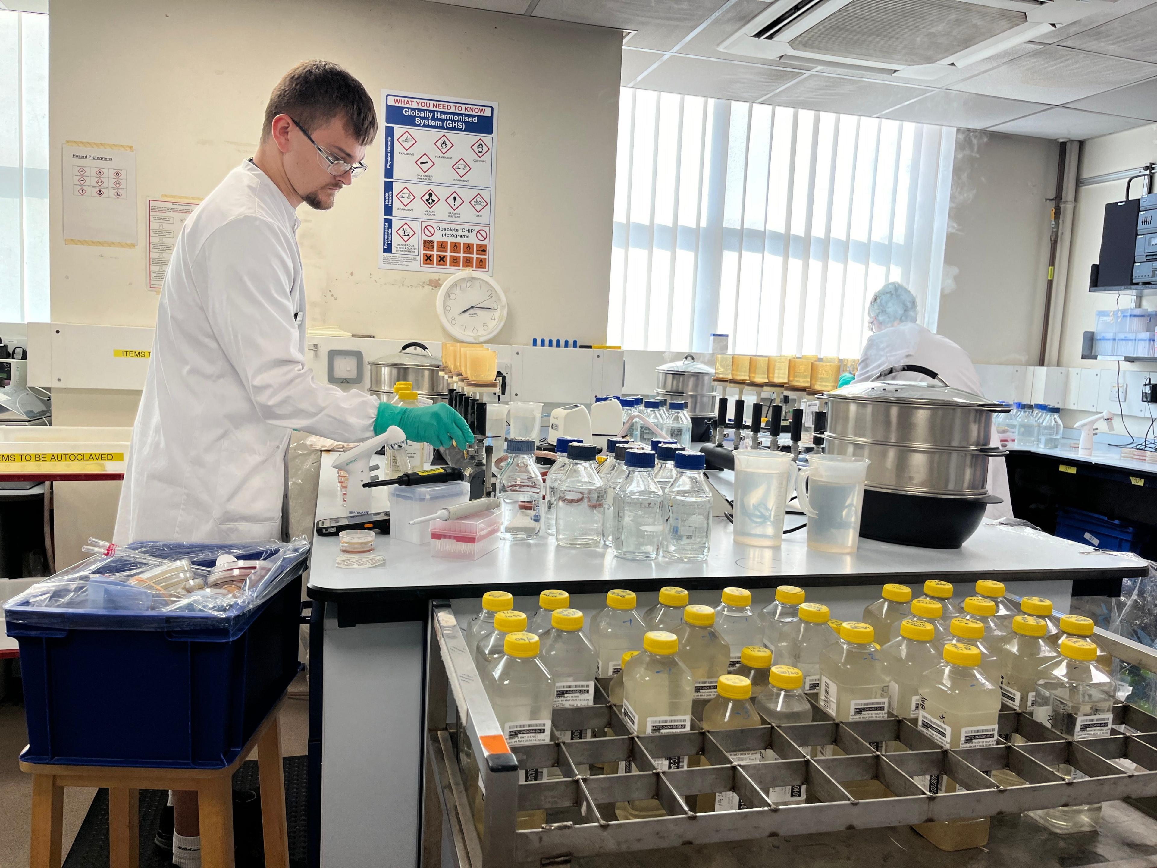A man clad in a white jacket and wearing glasses conducts water testing at the Starcross laboratory in Devon.