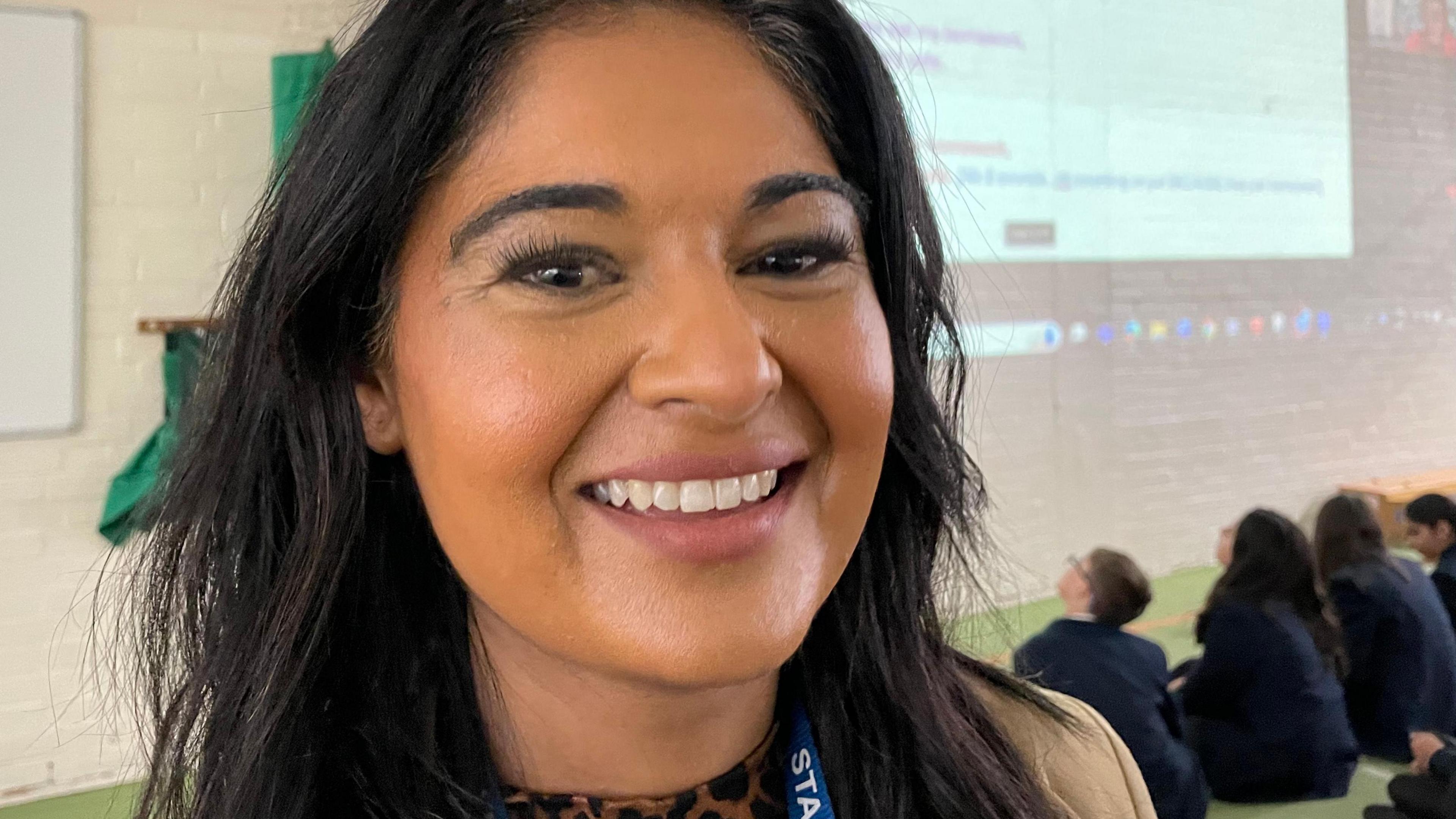 Ru Dalal, literacy lead at Roundhill Academy, standing in front of a projector screen and children looking up at it