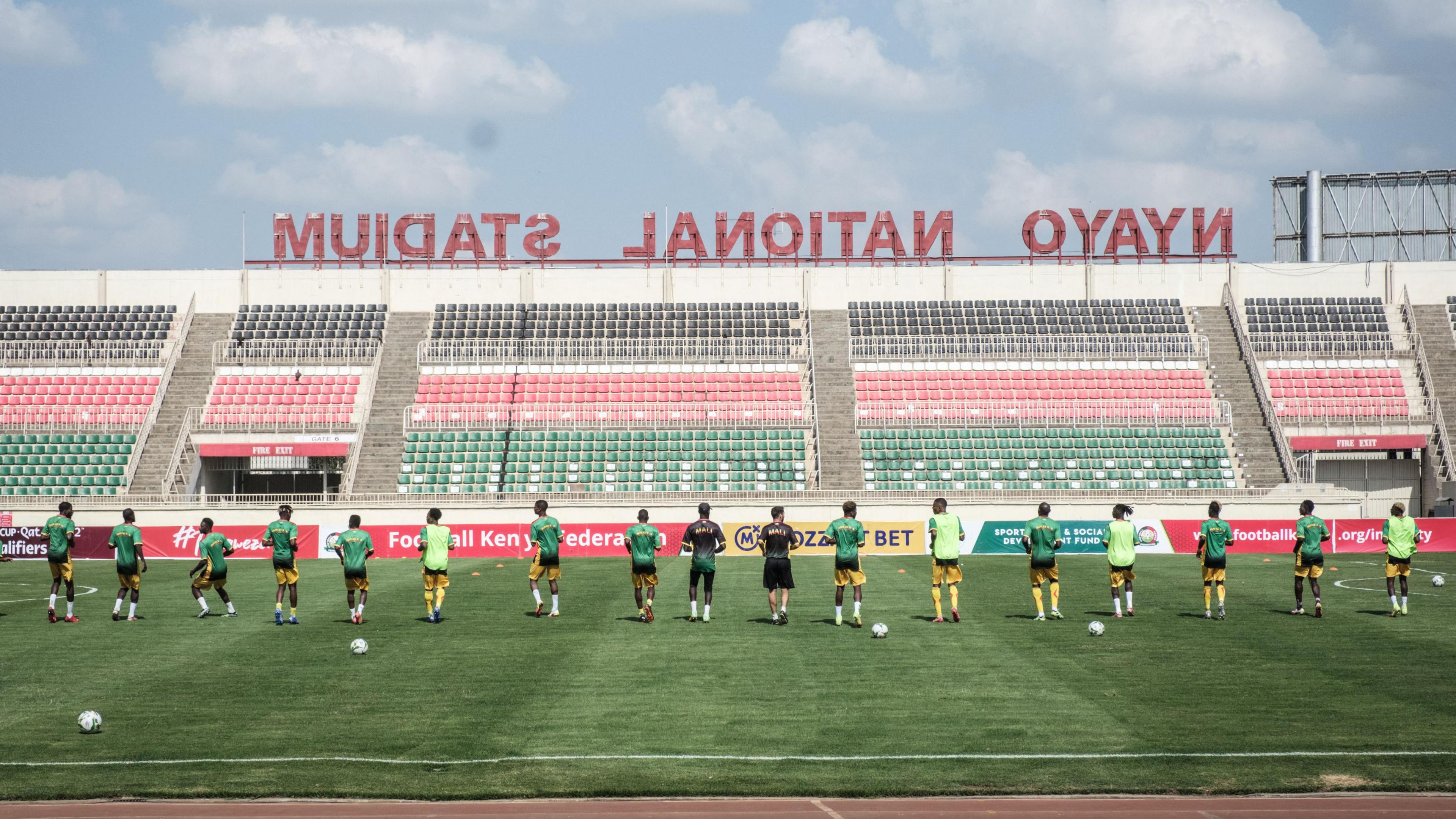 Mali's players dressed in green, yellow and black warm up in Kenya's Nyayo National Stadium which has green, black and red seats, before the 2022 World Cup qualifier football match between Kenya and Mali in 2021