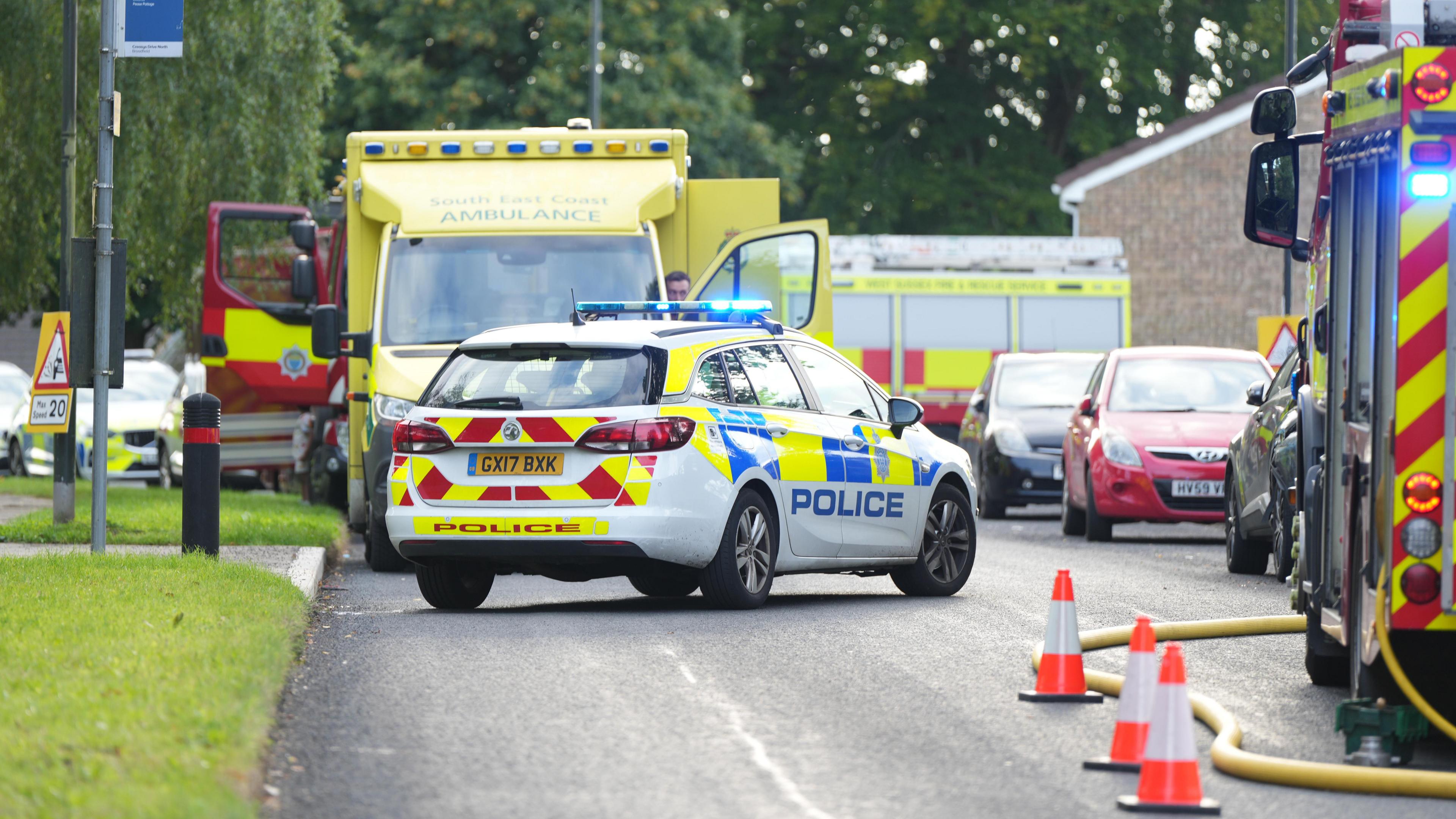 A police car is parked outside a house, along with ambulances and fire engines 