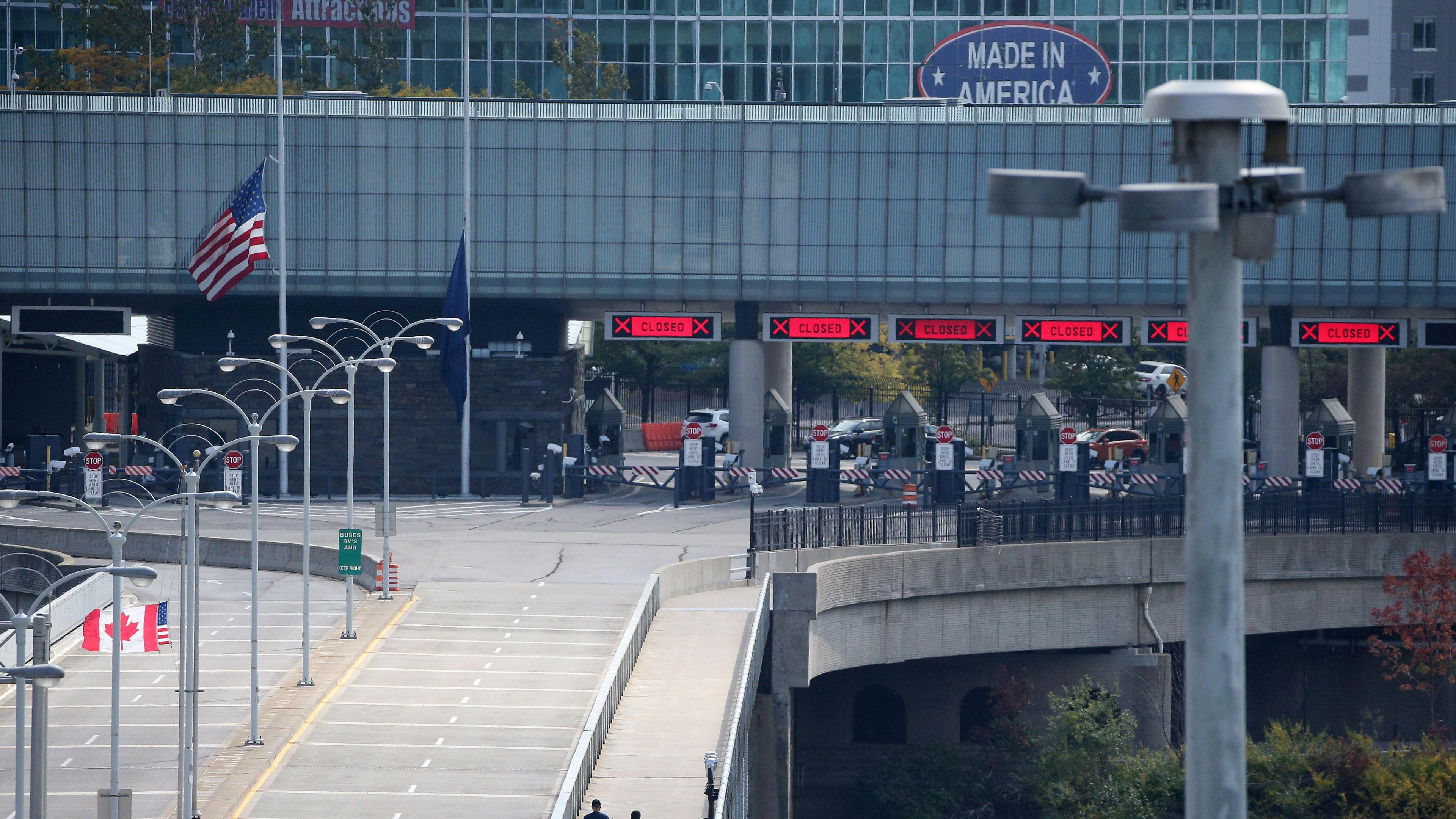 Two people walk across a bridge towards customs