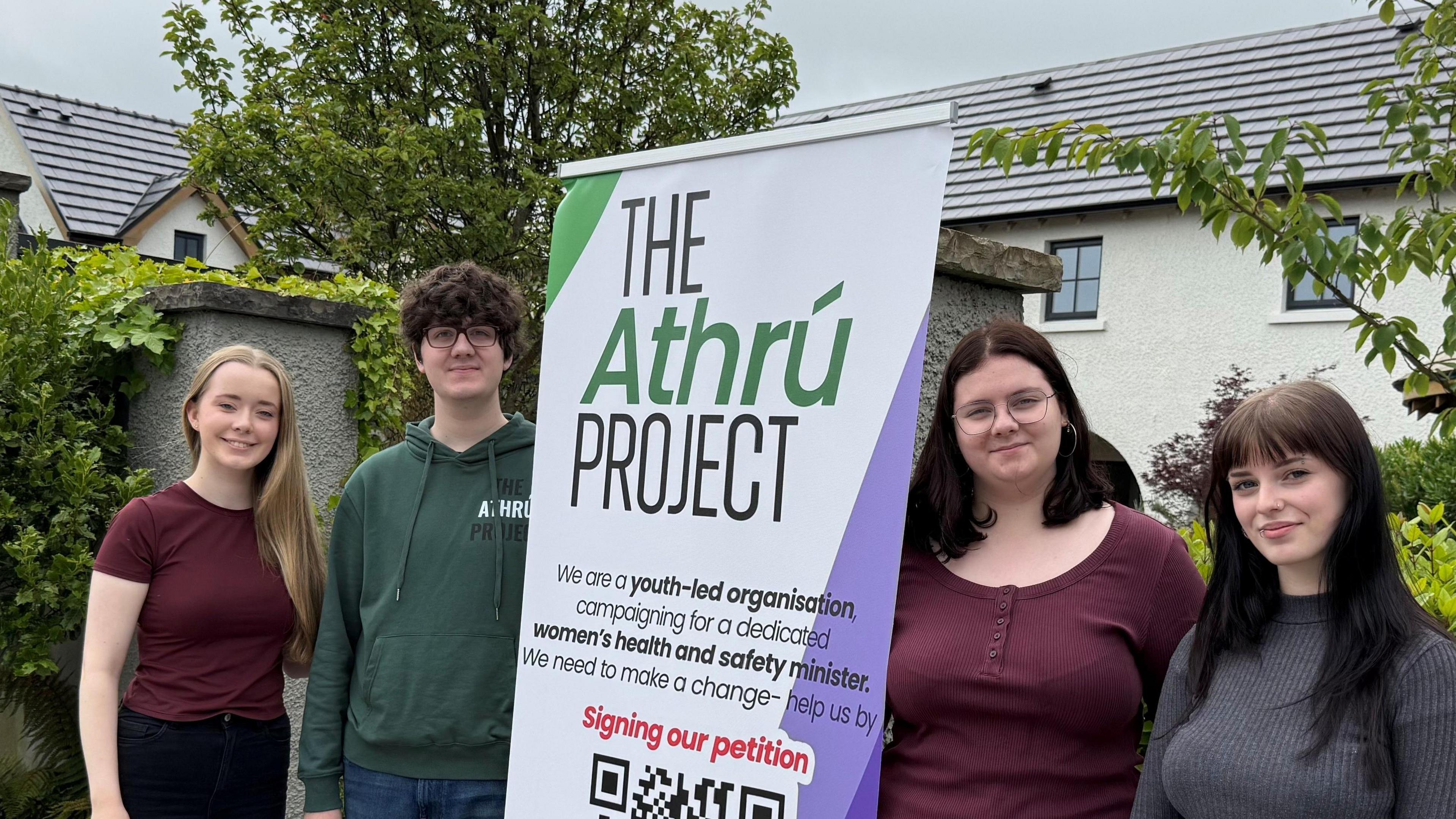 Four young people standing around a poster which says 'The Athrú Project'