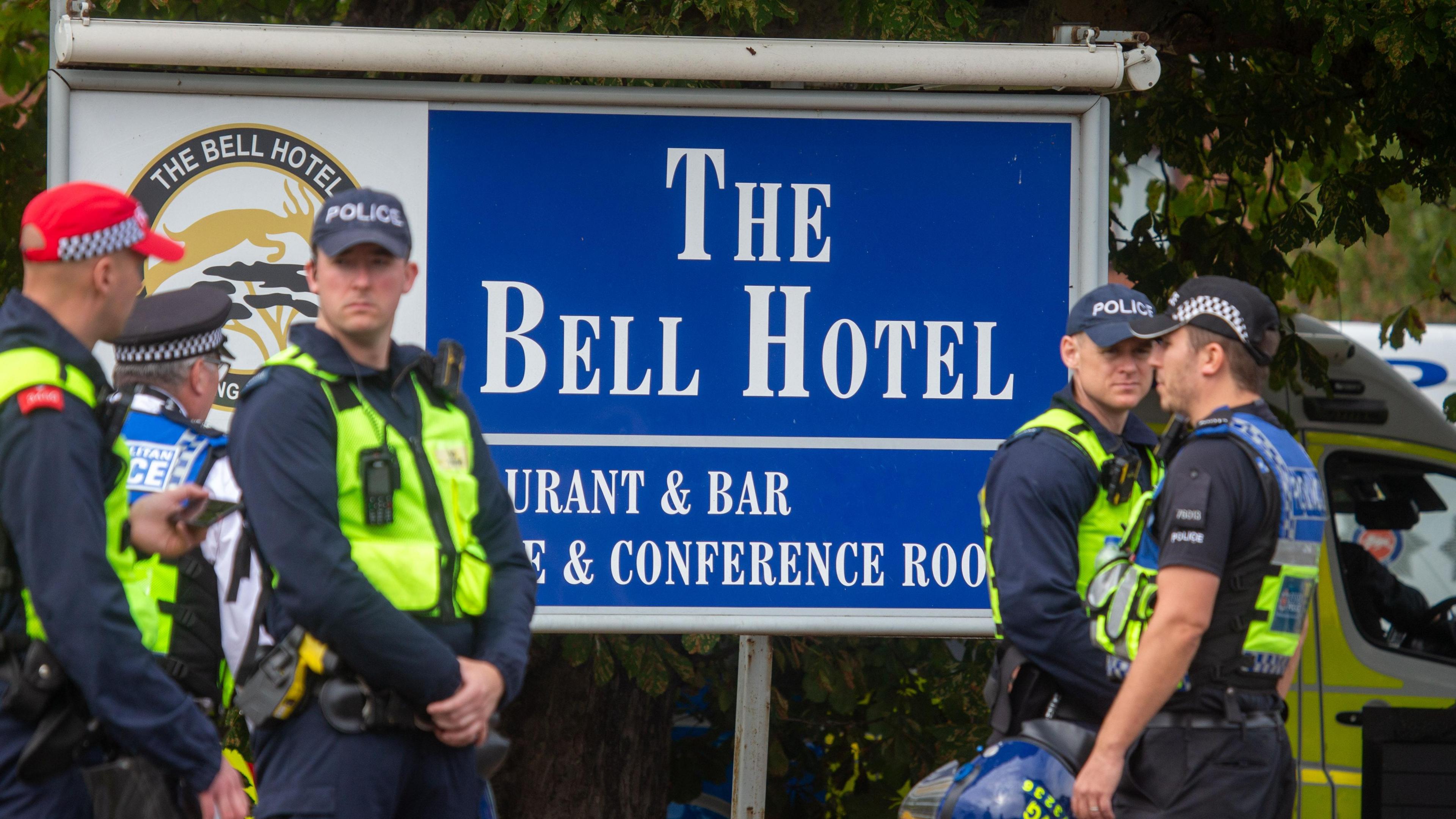 Police officers stand near a sign for the Bell Hotel