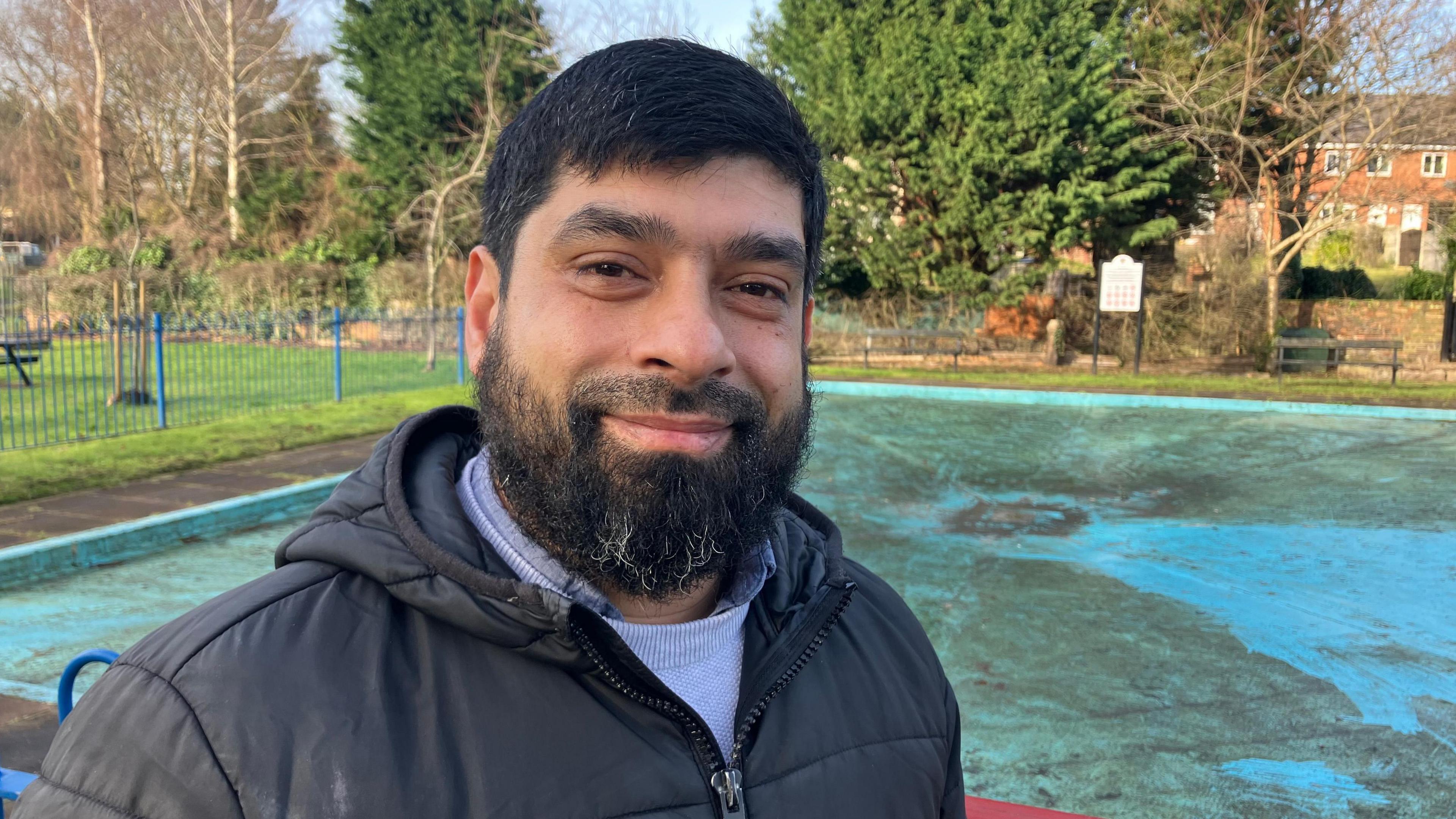 Syed Miah stands by the railings surrounding the closed-off paddling pool in St George's Park.