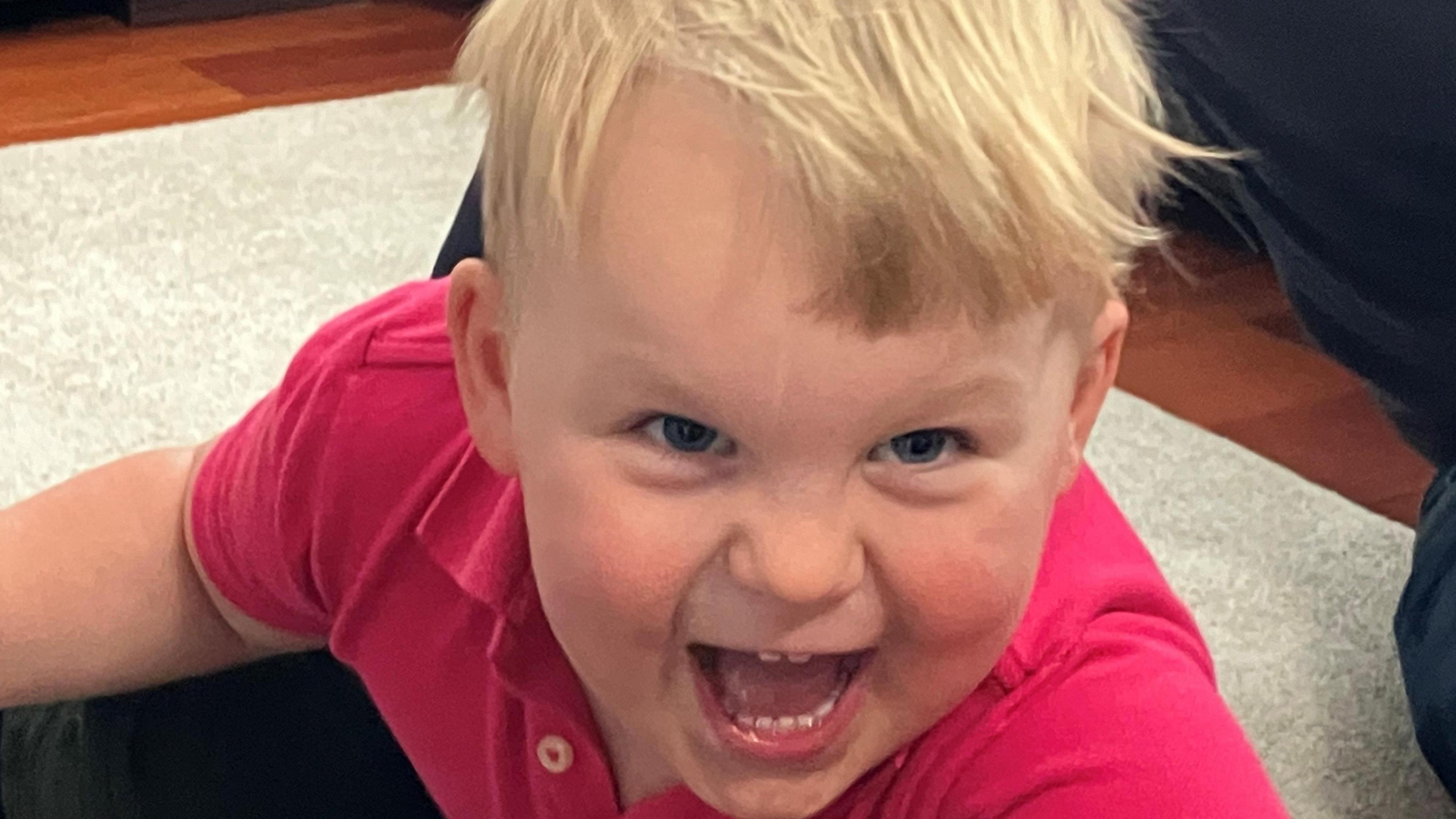 Reuben in a red shirt smiling towards the camera