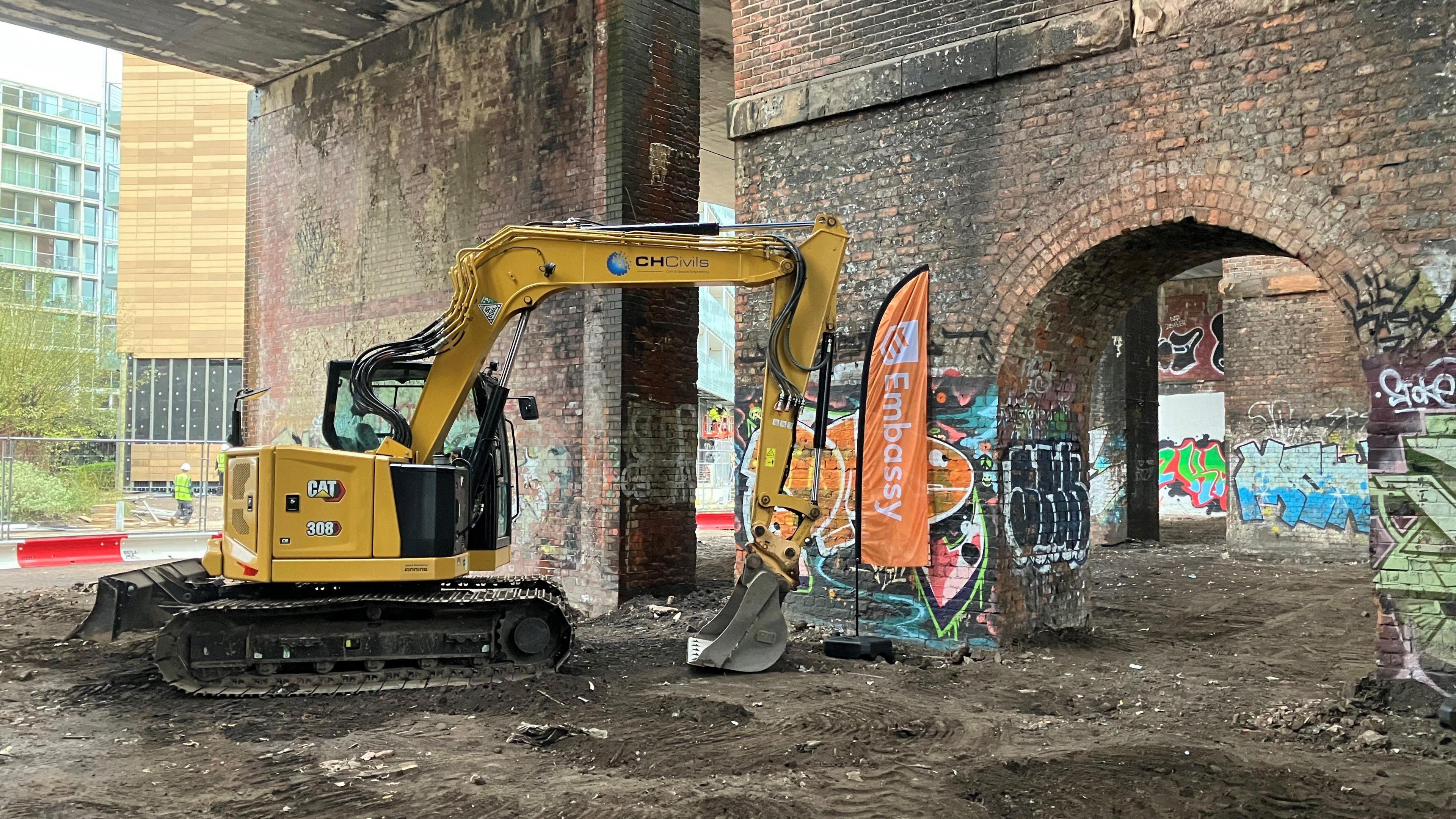 Photograph of a bulldozer underneath railway arches in Manchester