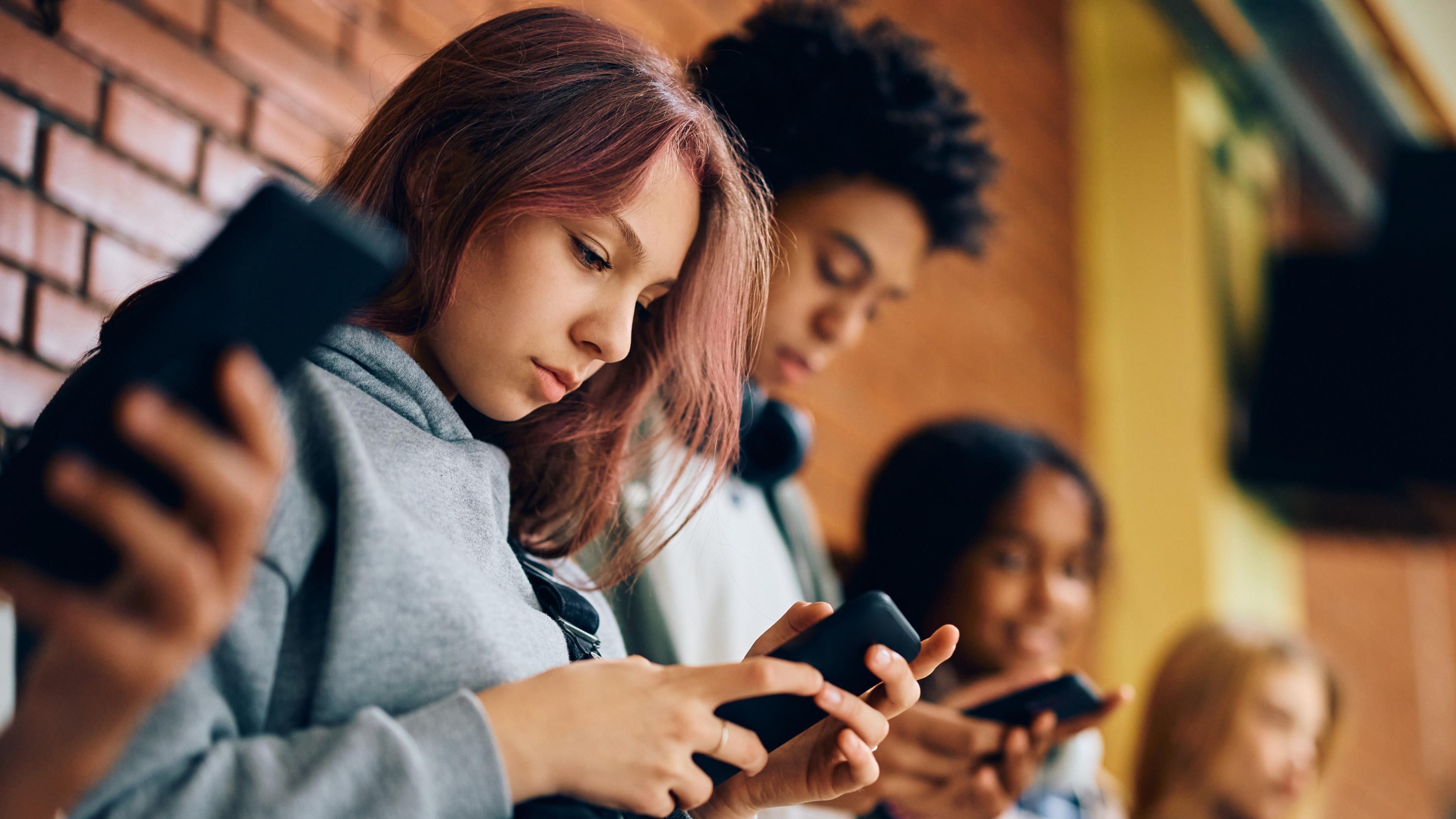 A group of teenagers looking at their mobile phones.