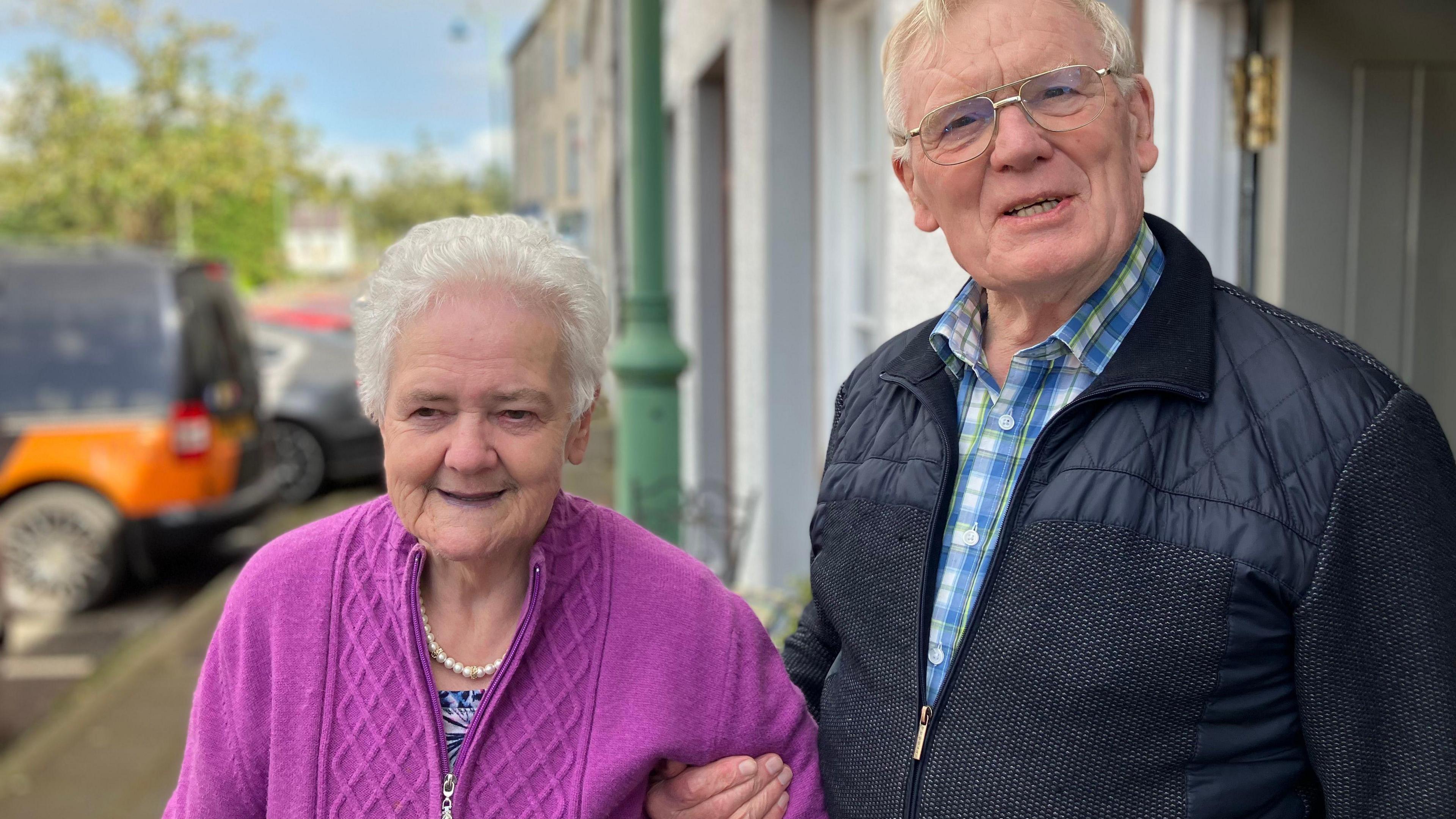 Derek Johnston with his wife in Ederney village in County Fermanagh. Mr Johnston's hand is under his wife's arm, supporting her