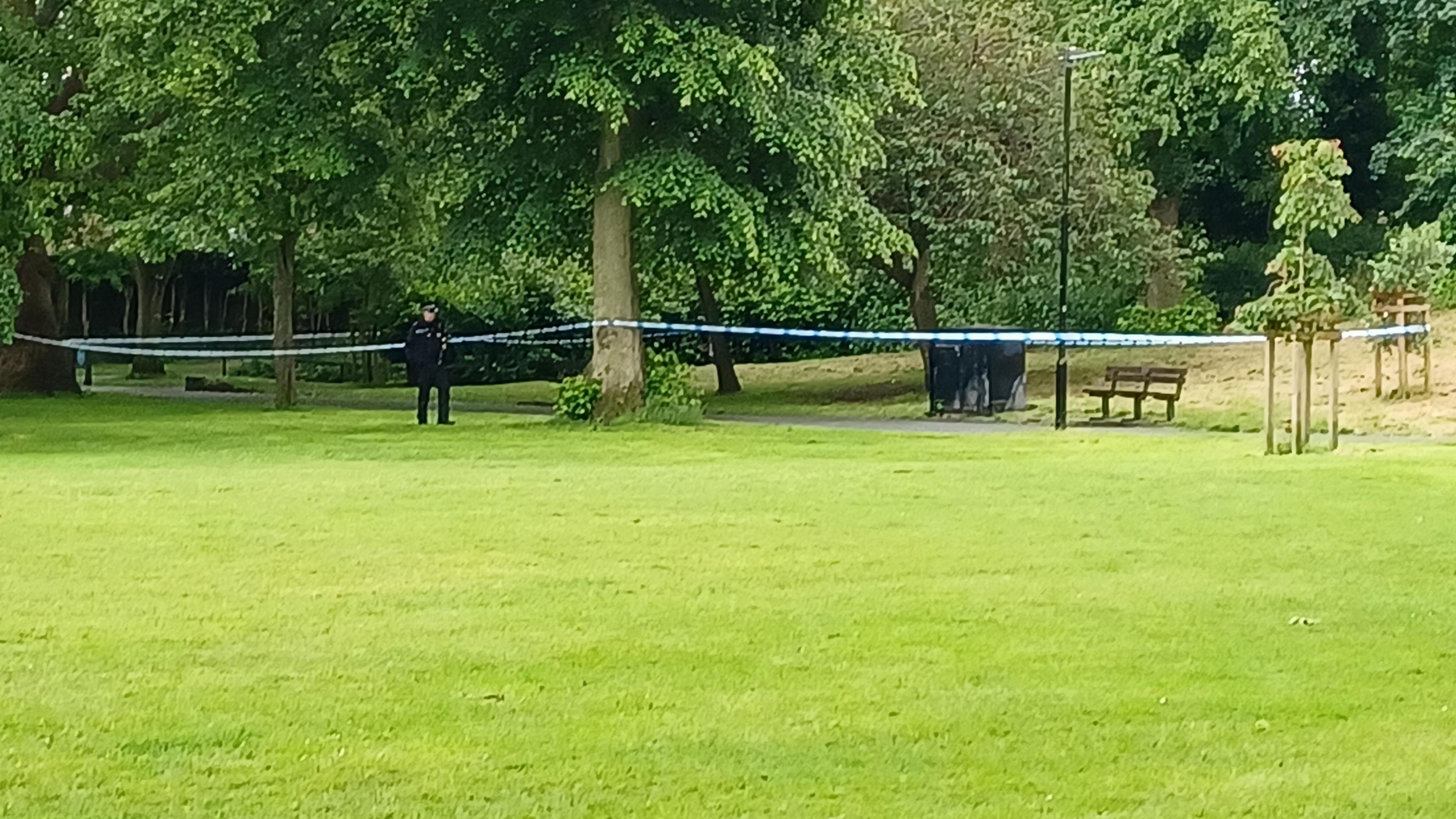 Police officer in park next to a cordon