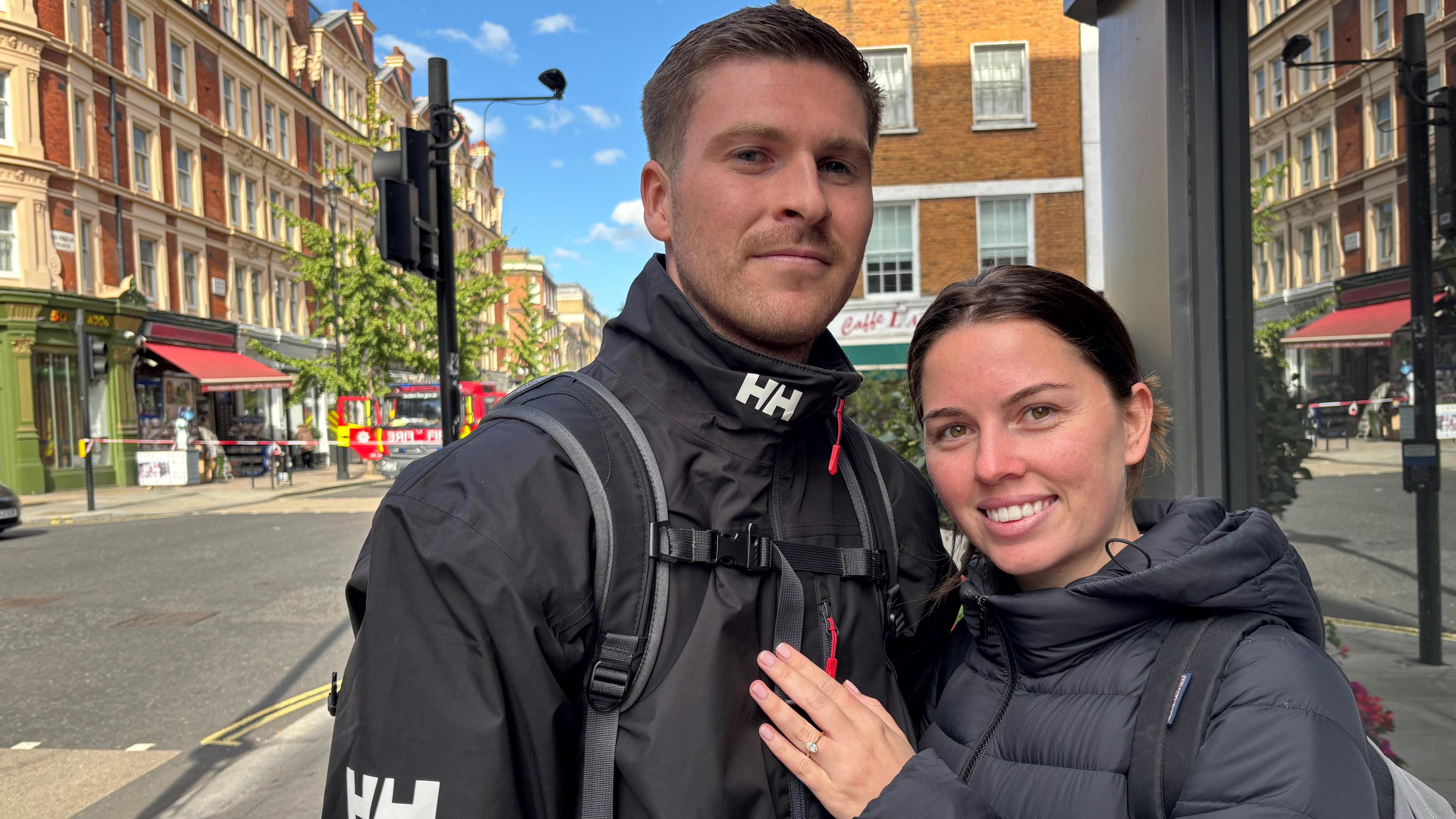Lachlan Dinham and his fiancée in black coats and wearing rucksacks.