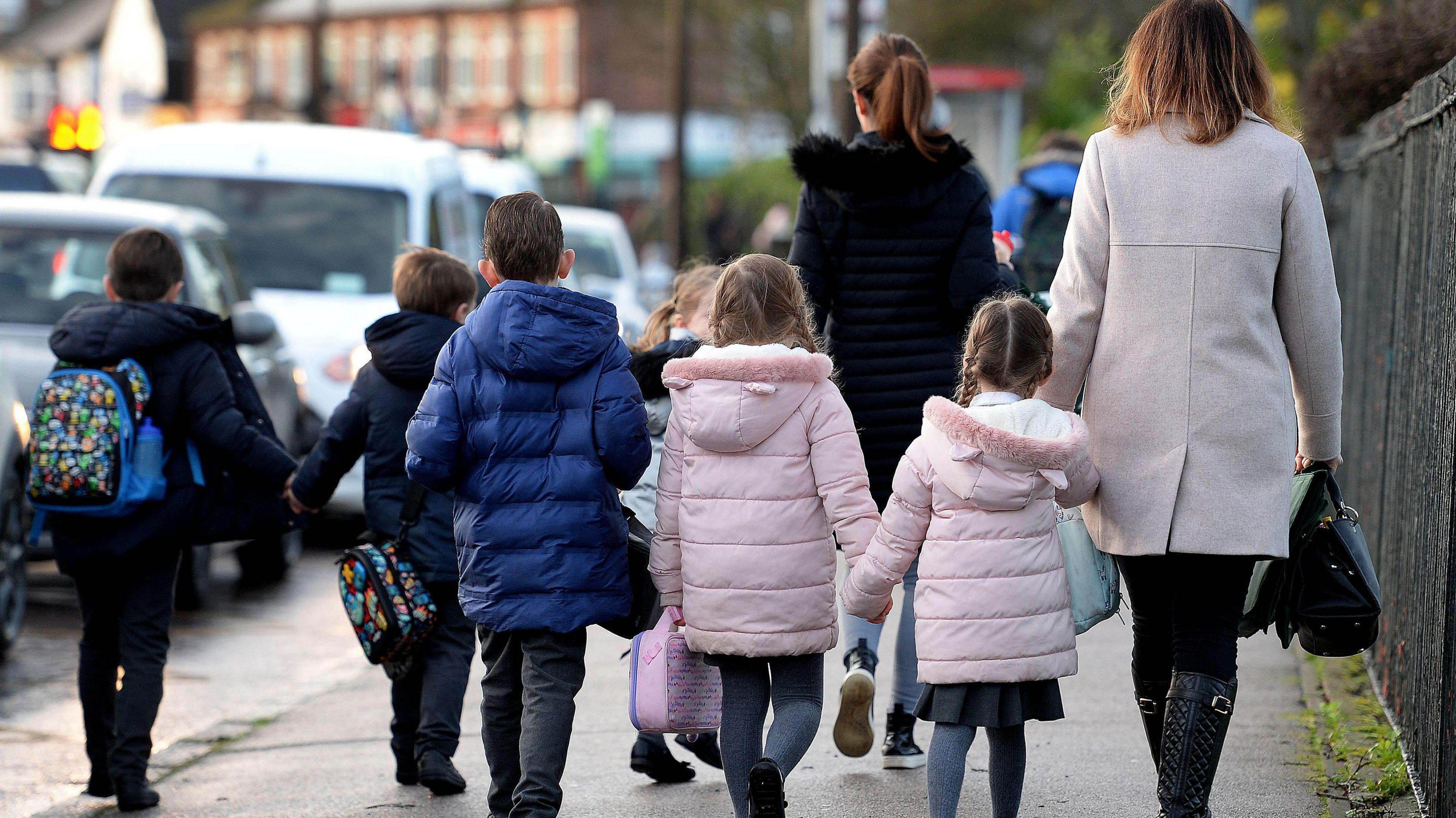 A couple of parents walk several children to school.