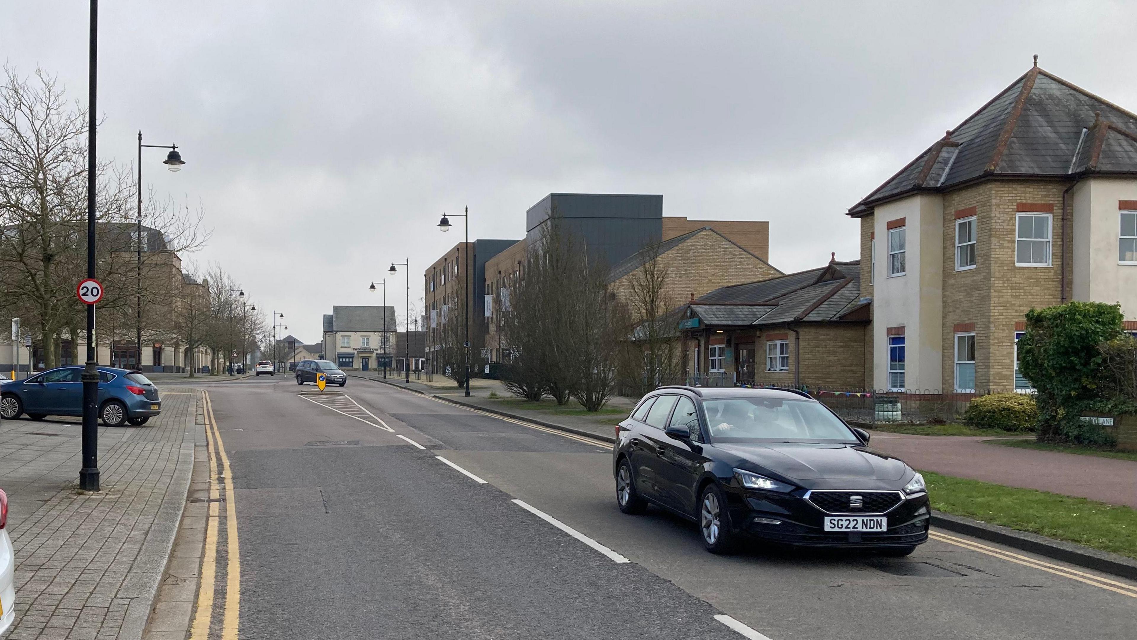 A road with cars on in Cambourne high street