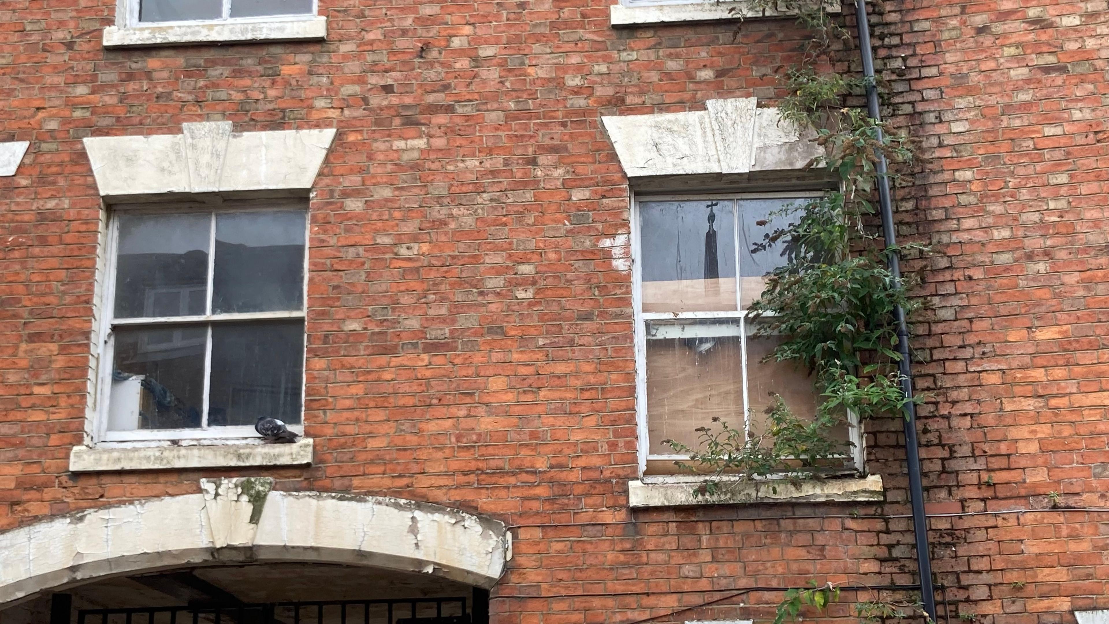 Brick-built pub building with leaves visible around the edge of a window 