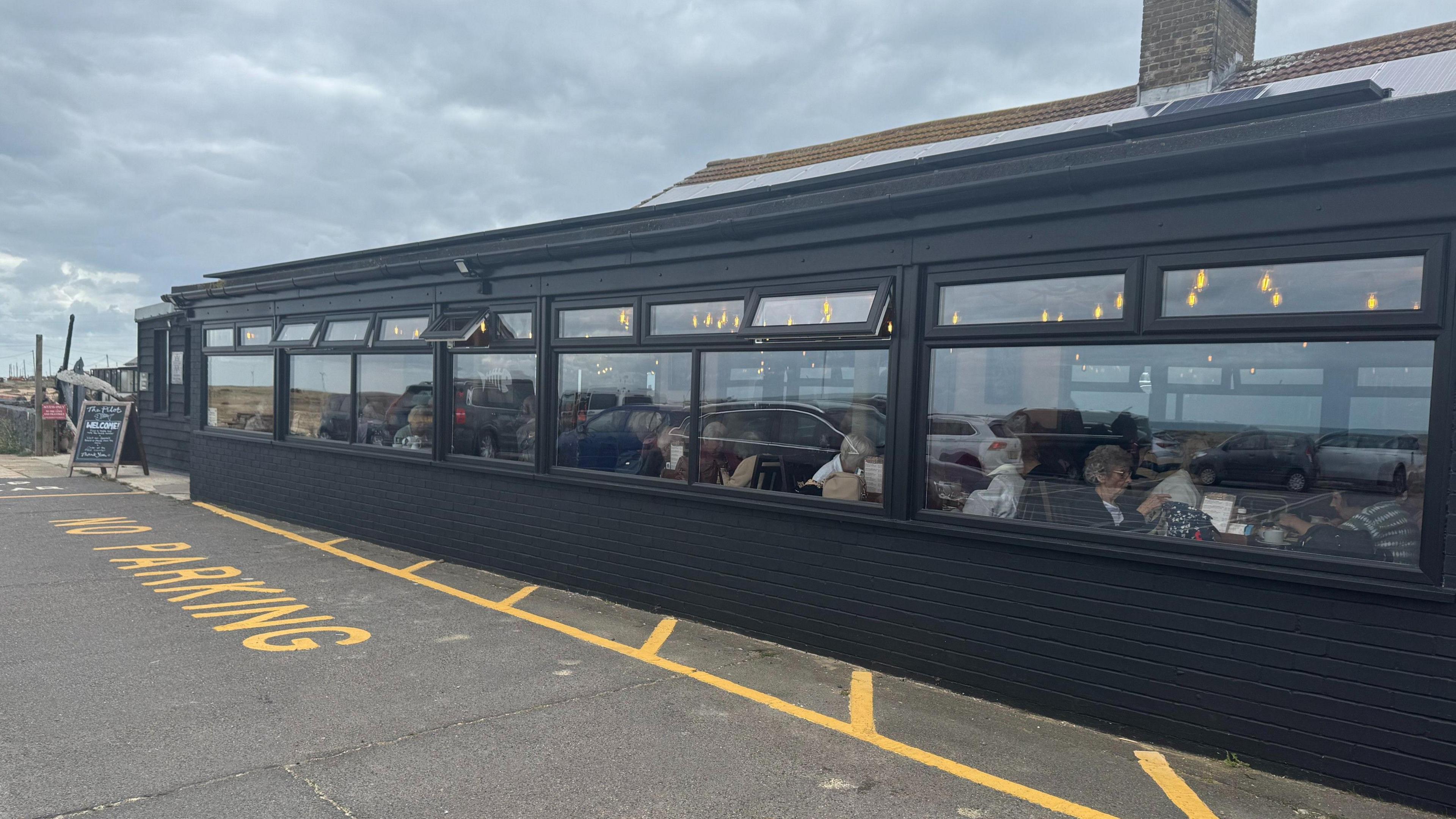 The restaurant of the restored Pilot Inn, viewed from the outside, filled with customers on the inside.