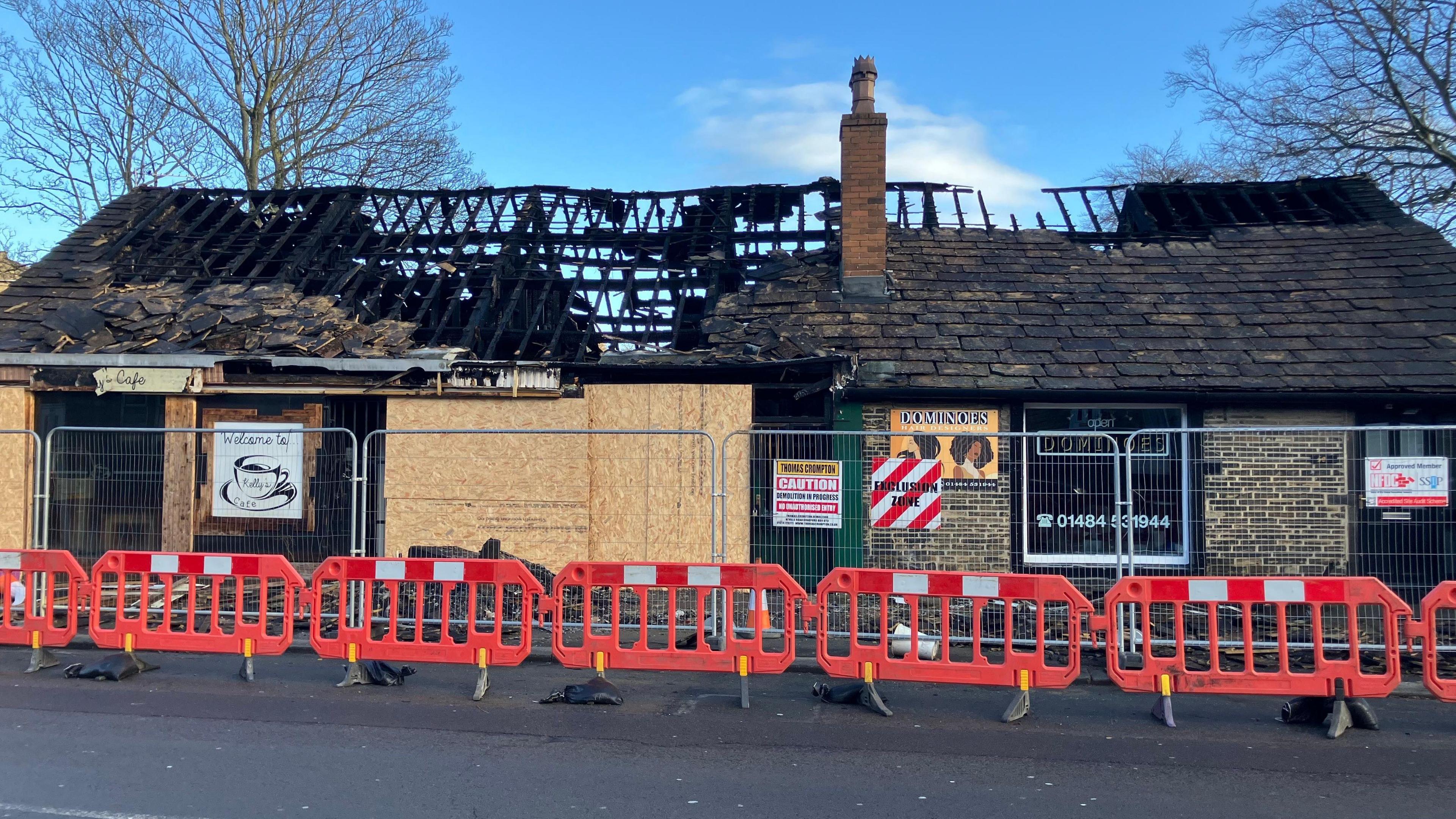 An exterior view of the building which houses Kelly's Cafe, the florist and Dominoes Hair Designers. It's roof is partially missing due to fire damage.