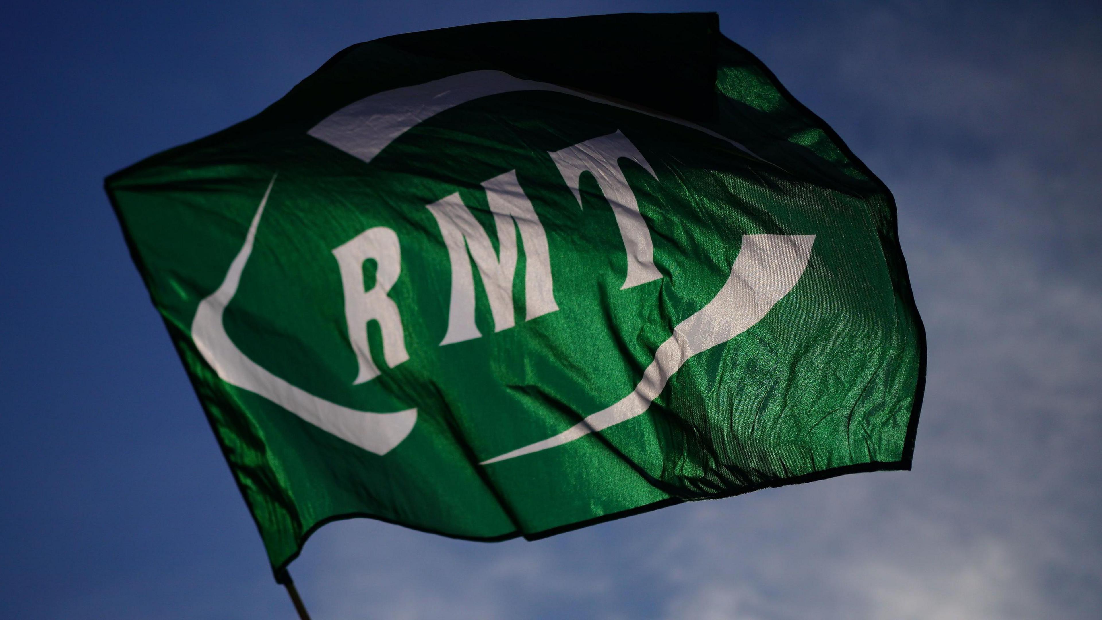 An RMT flag waving against a blue sky. The RMT logo is in white lettering against a green background.