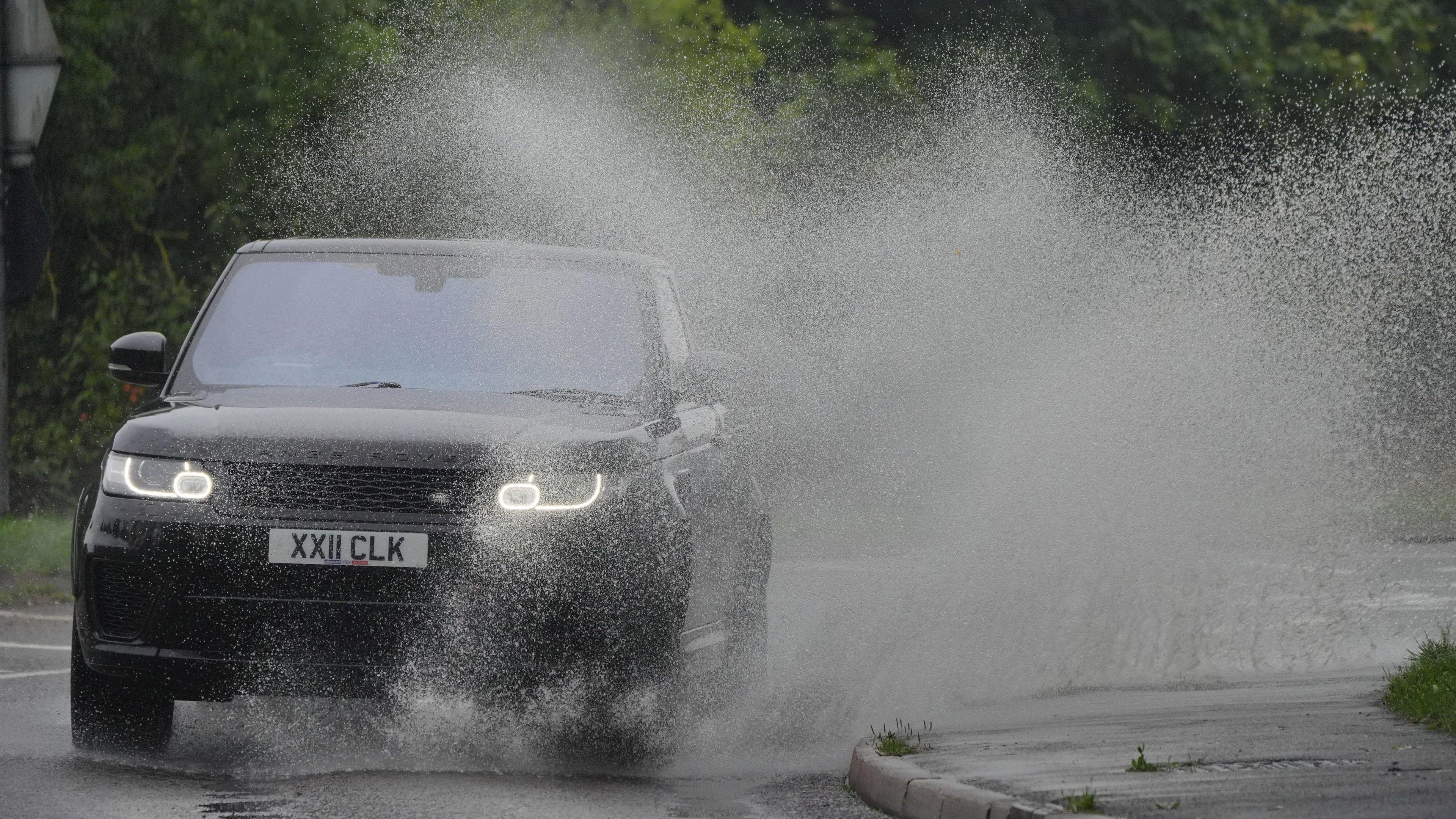 a car driving through the rain splashing water up in the air