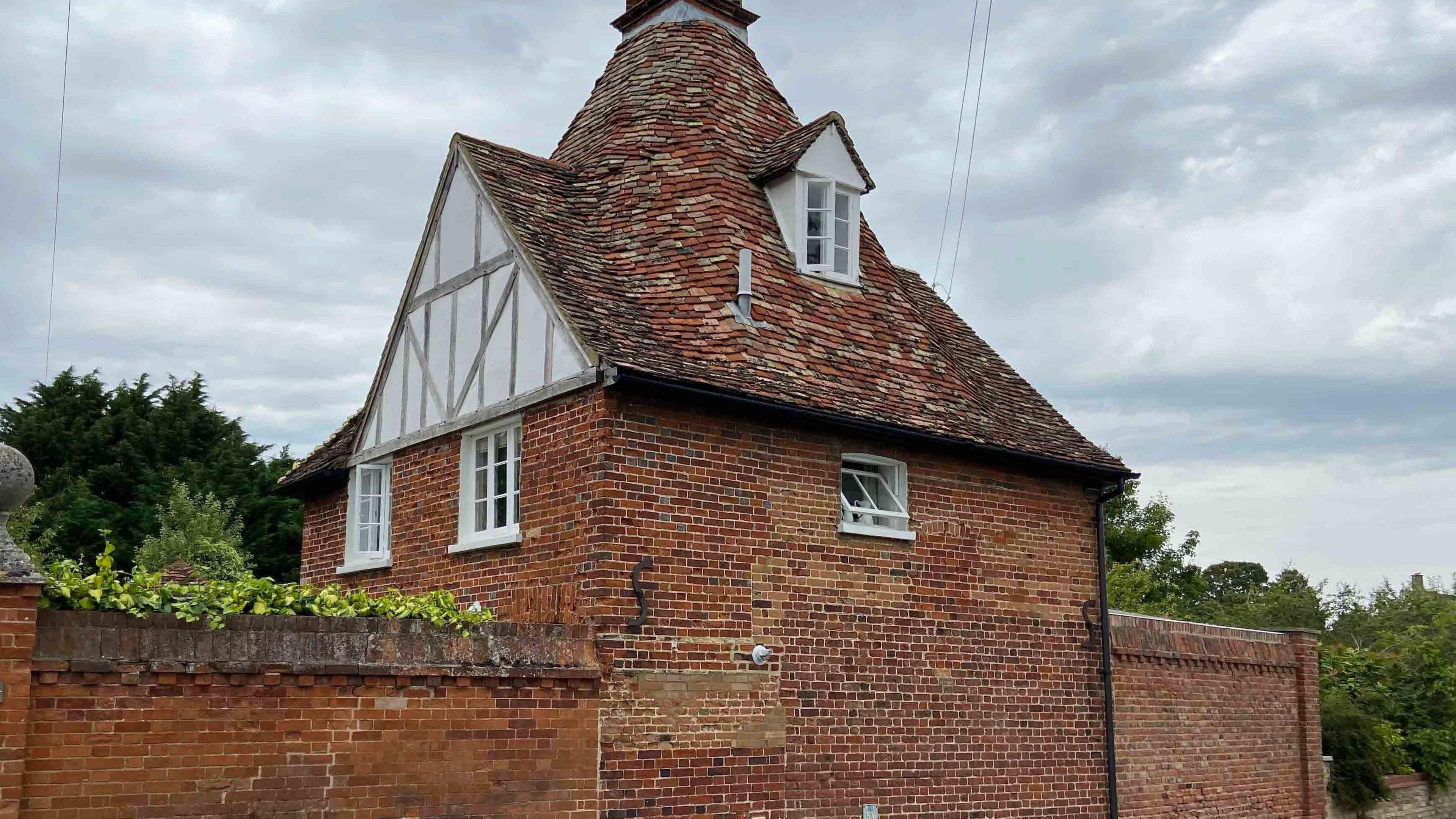 Recent photo of the house where Louis Leakey lived in Foxton. It has been built with red brick and has an unusually shaped roof with lots of different coloured slates.