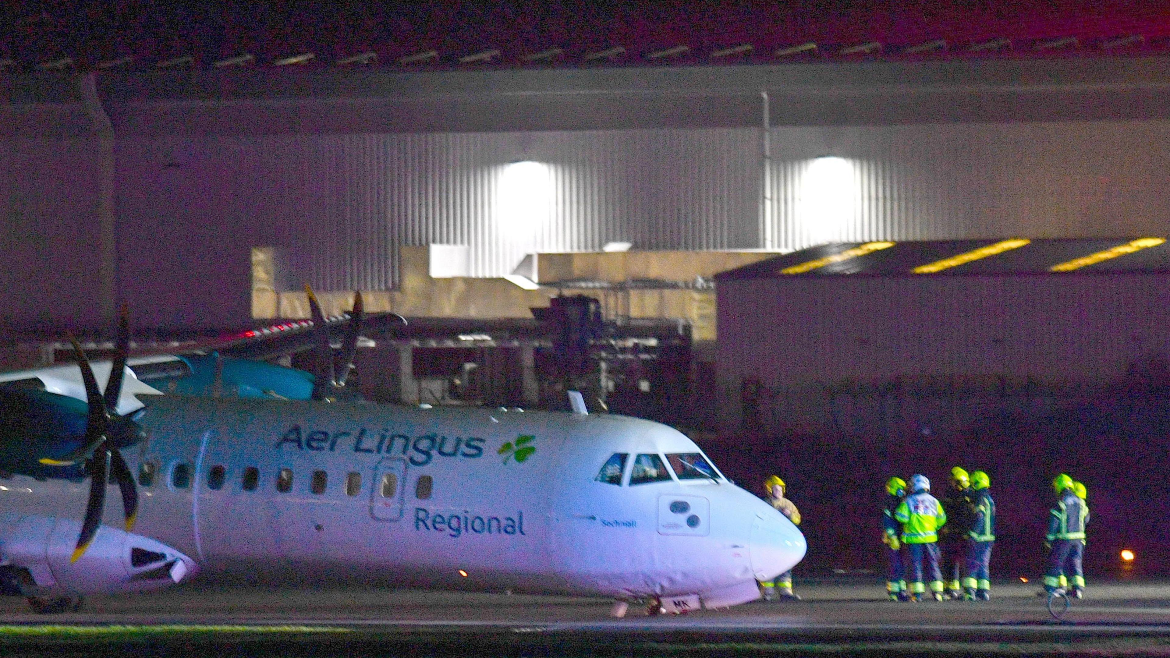 An Aer Lingus plane on the runway at Belfast City Airport on Sunday night, flanked by emergency crews in high-viz clothing.   The plane's nose wheel appears to have collapsed during landing. 