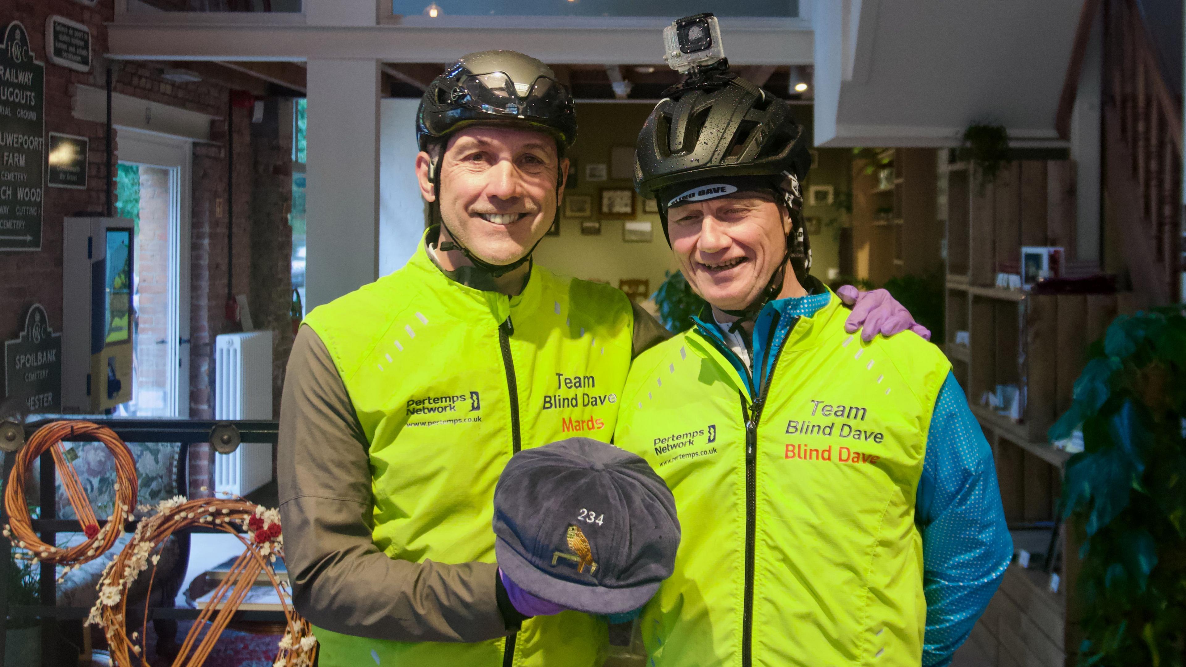 Two men in lime green cycling clothing and a replica football cap