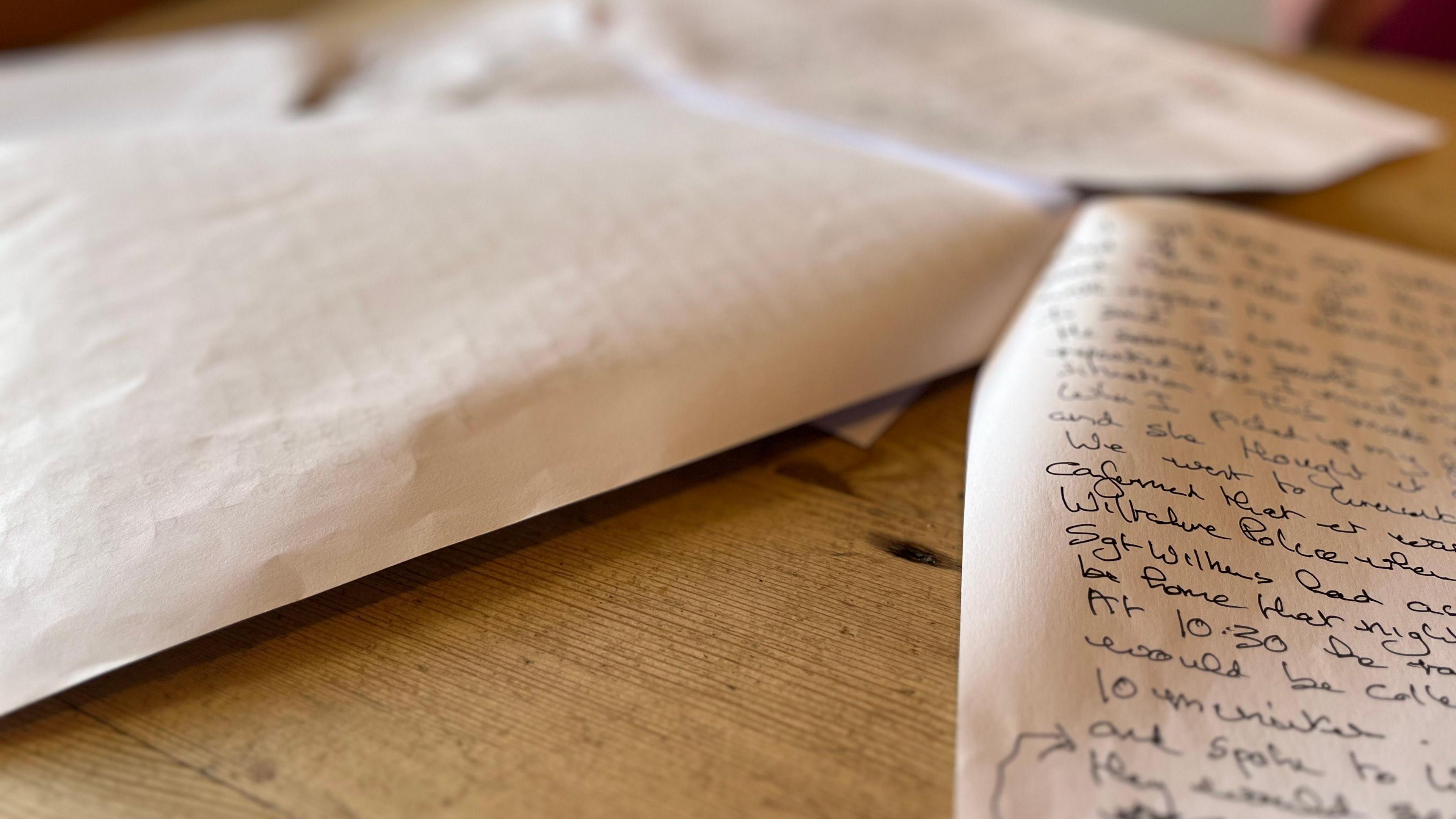 Pieces of paper with handwritten notes lying on wooden table.