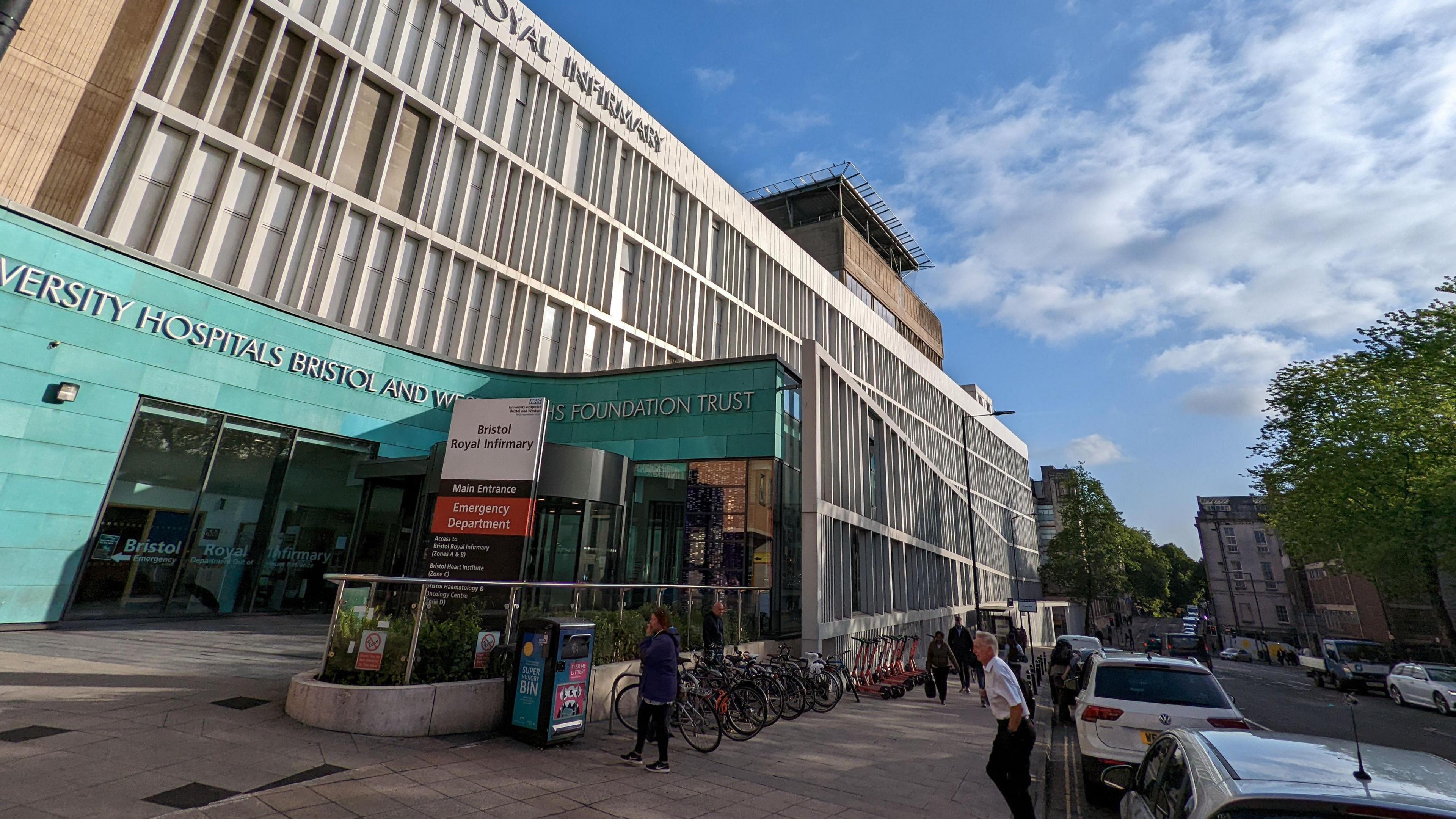 A view of the outside of the BRI - a grey and blue building, with a blue sky behind it, and cars parked at the side of the road