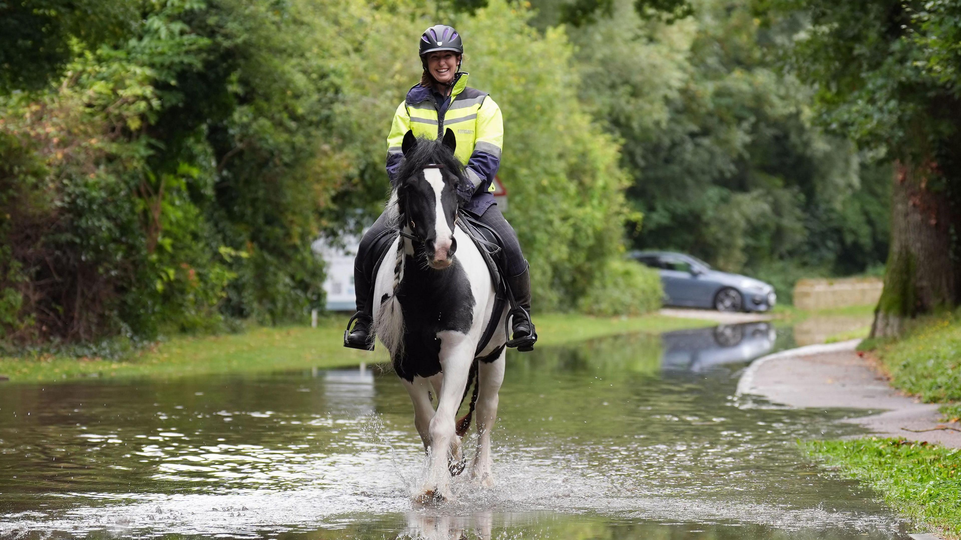 A rider and her horse making their way along a flooded road in Bedfordshire