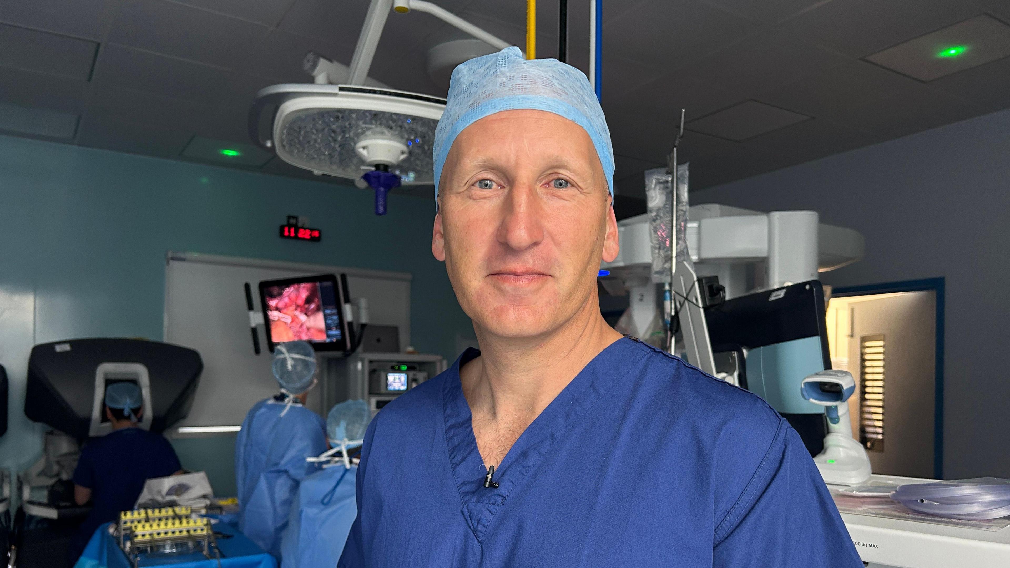 A surgeon wearing a blue gown and a blue hat in an operating theatre
