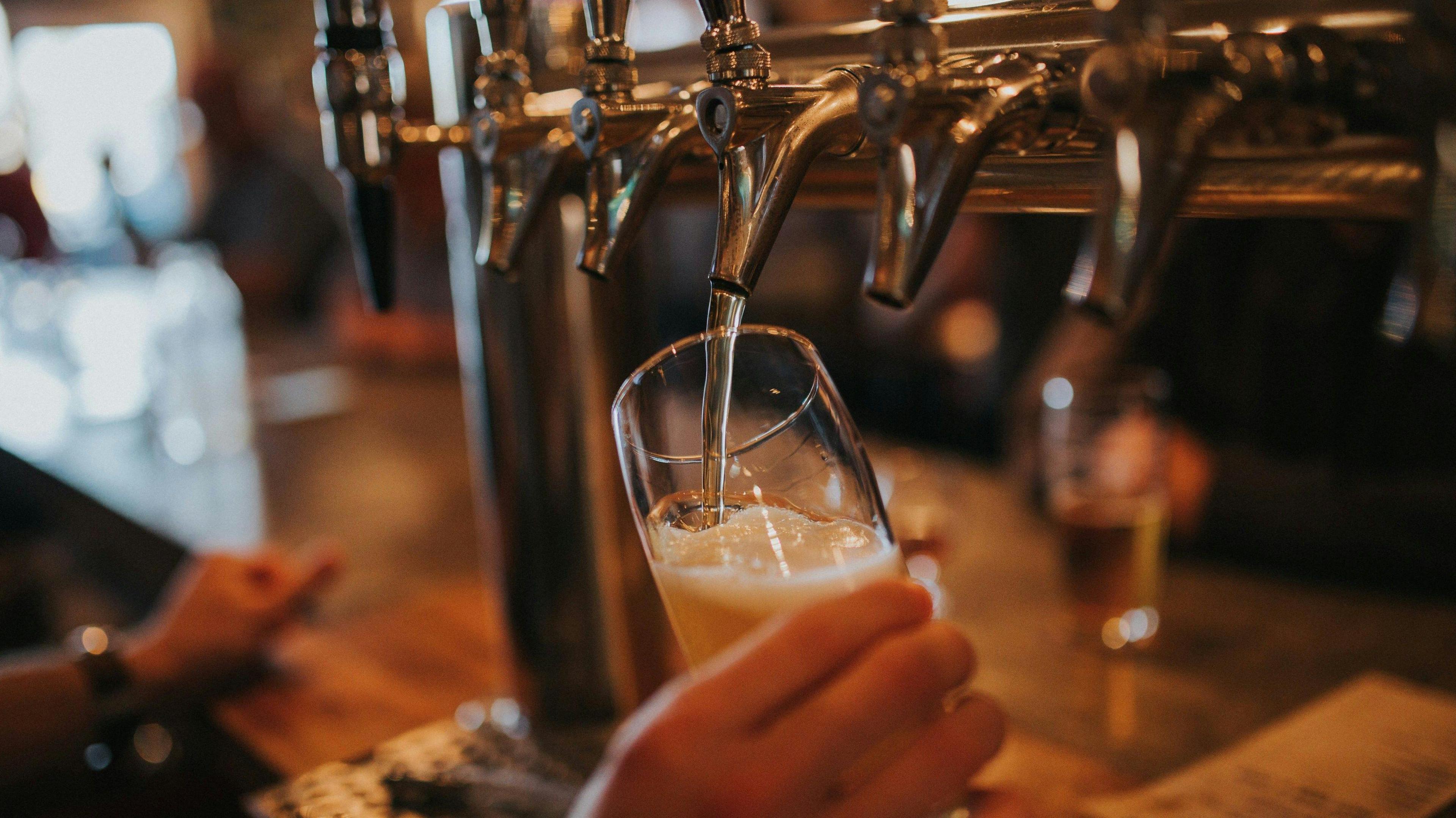 A drink is being poured from taps in a pub - it is a generic shot.