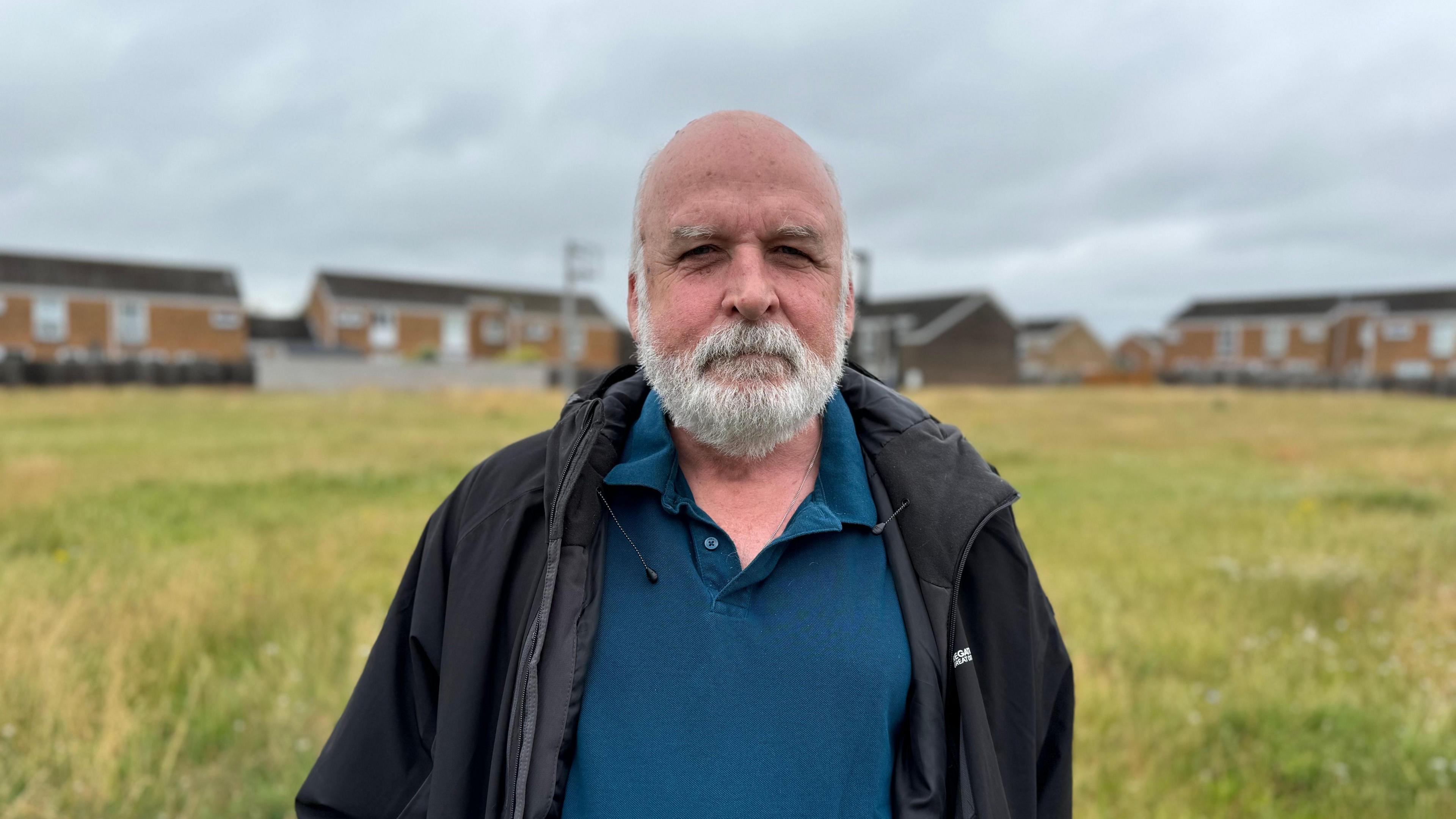 Garth Tolmie wearing an unbuttoned inky blue polo shirt and a dark waterproof jacket