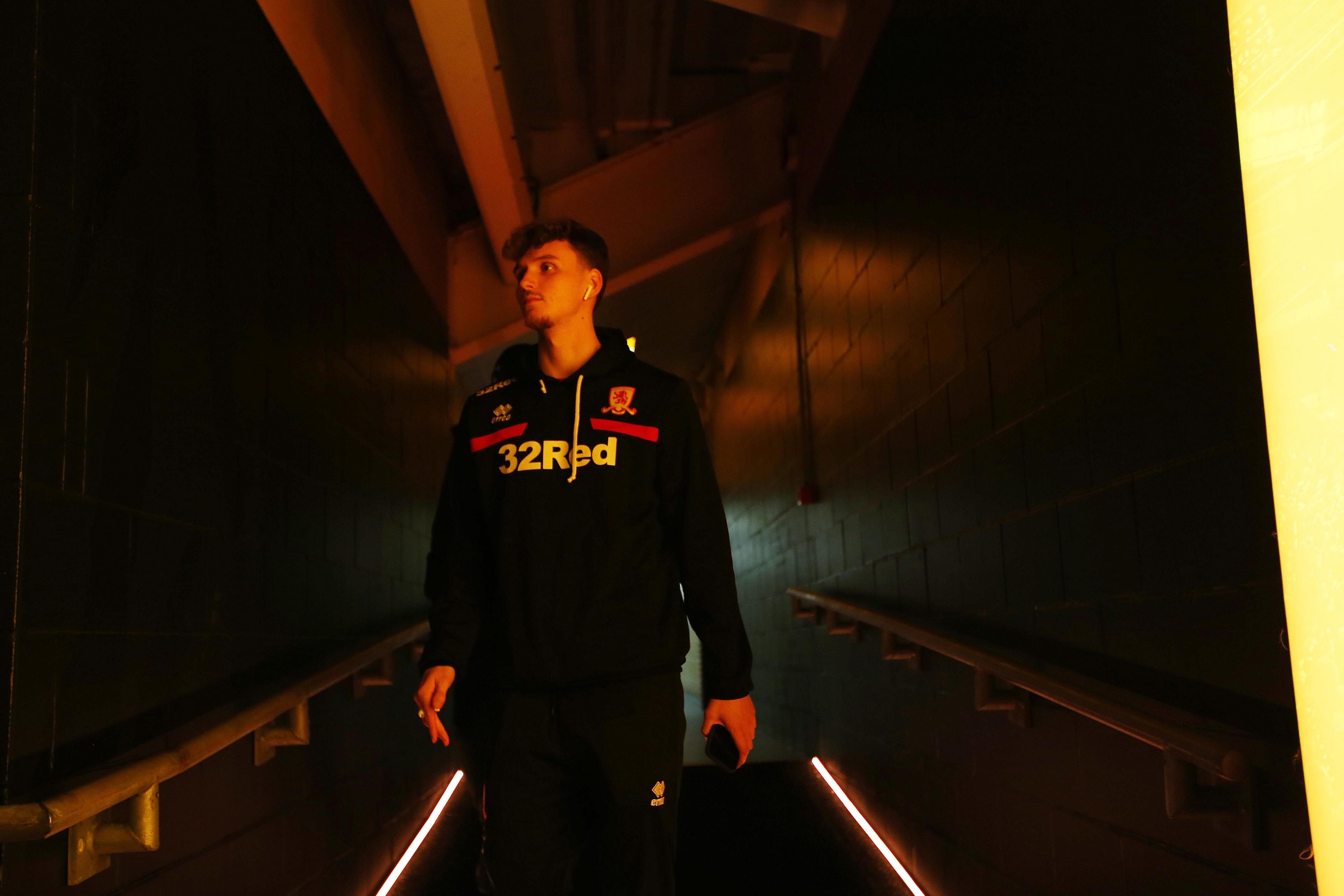 A player in a dark Middlesbrough tracksuit walks down a dark tunnel.